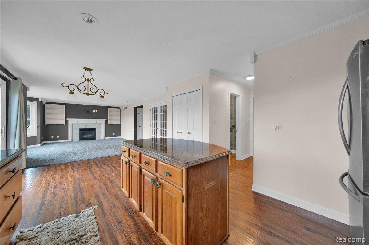 Open kitchen with a wood island and hardwood floors, adjoining a carpeted living room with a fireplace.