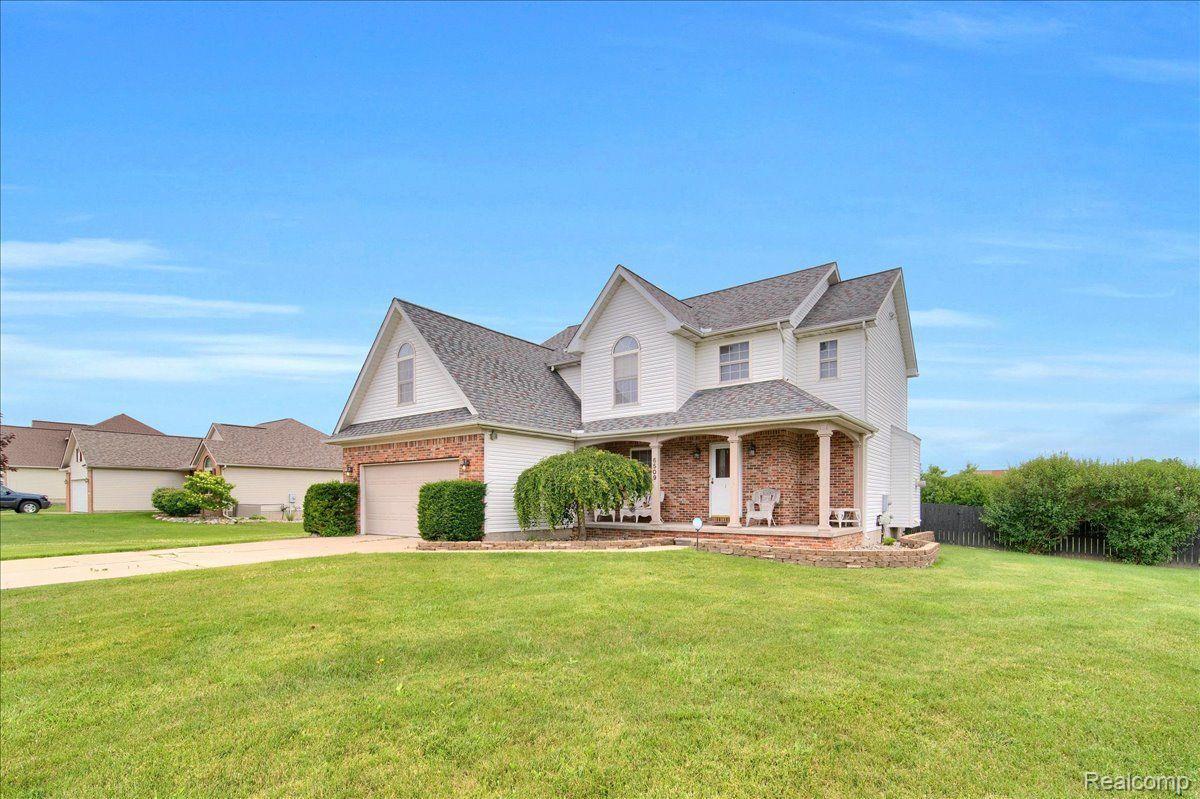 Two-story white-and-brick home with an attached garage, covered porch, and broad front lawn.