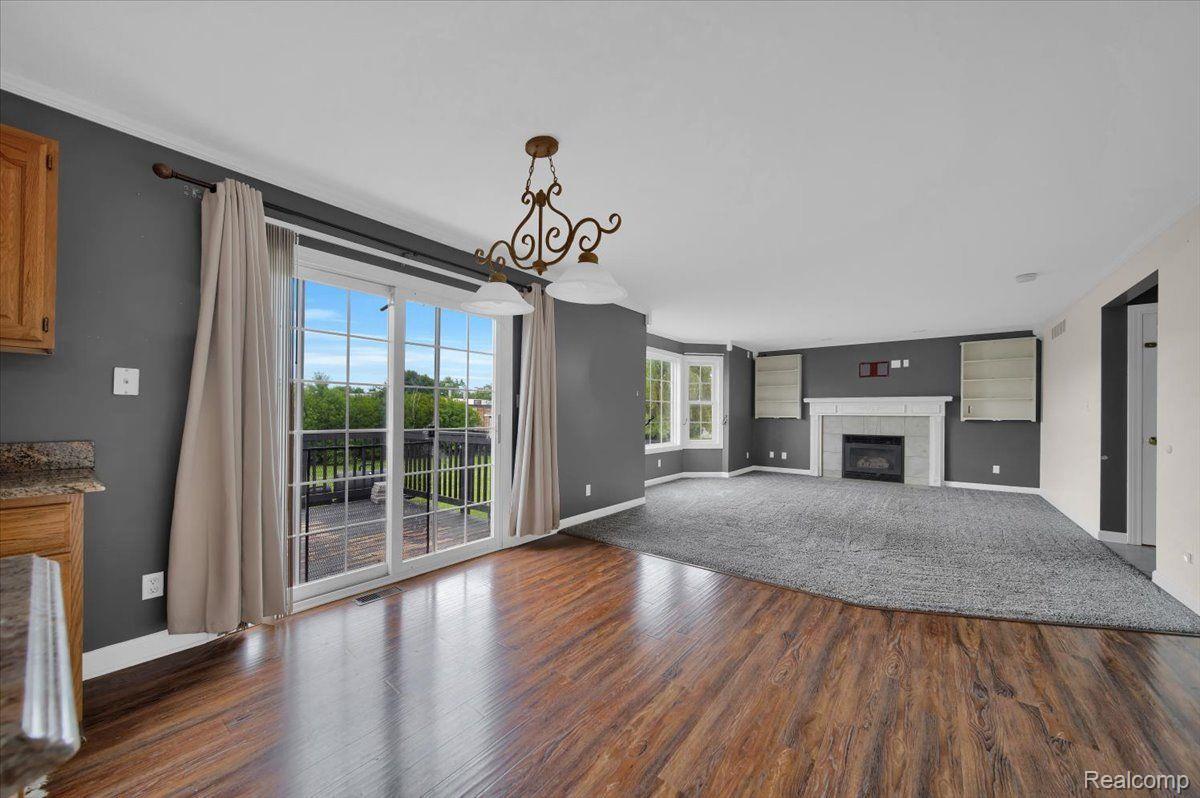 Vacant living room with a white fireplace, built-in shelves, and sliding glass doors to a balcony.