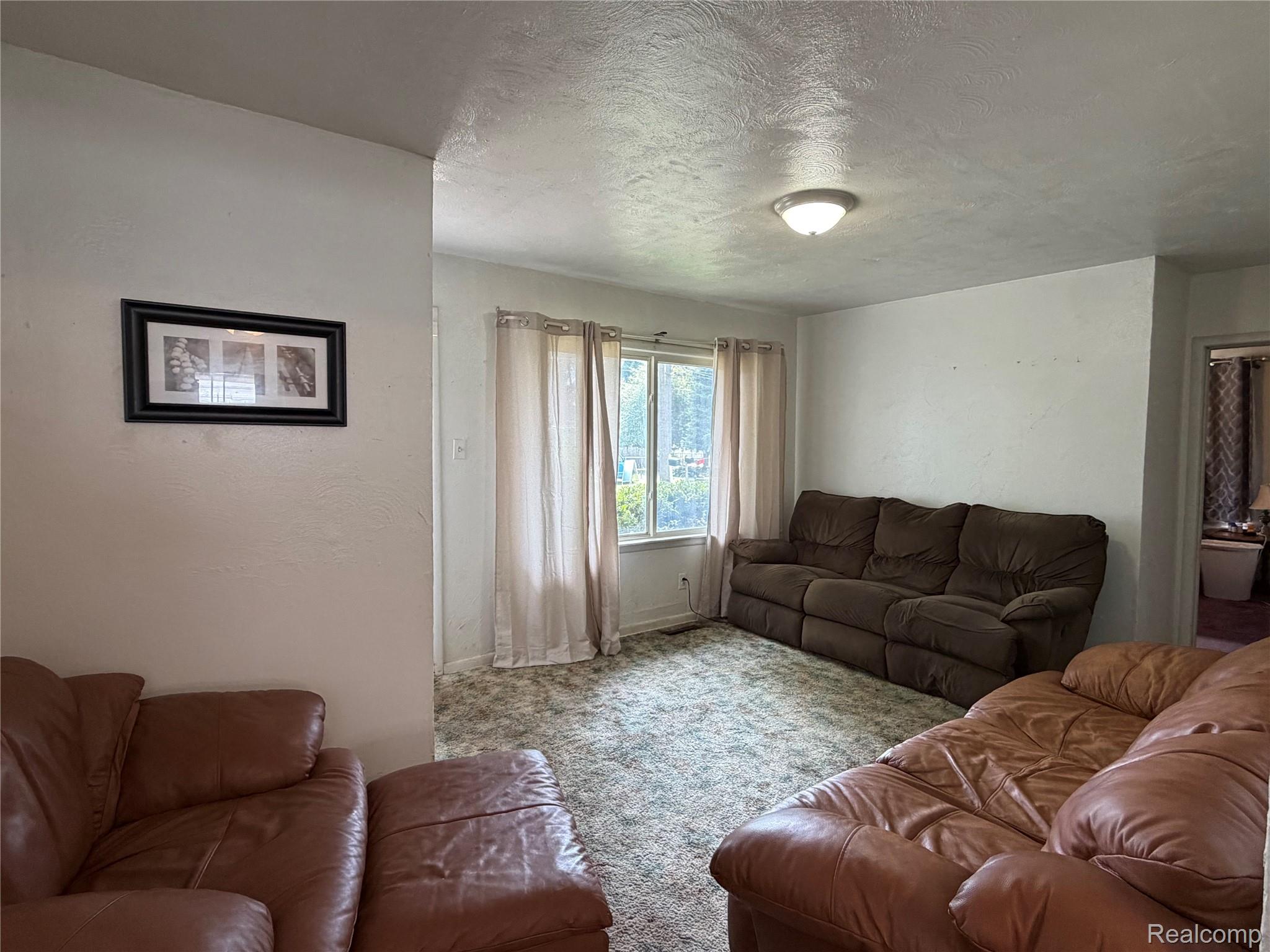 Living room with brown leather recliners, a matching sofa, and a curtained window.