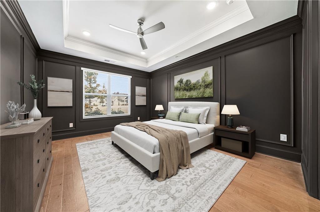 Staged bedroom with a white upholstered bed, dark paneled walls, and warm wood flooring.