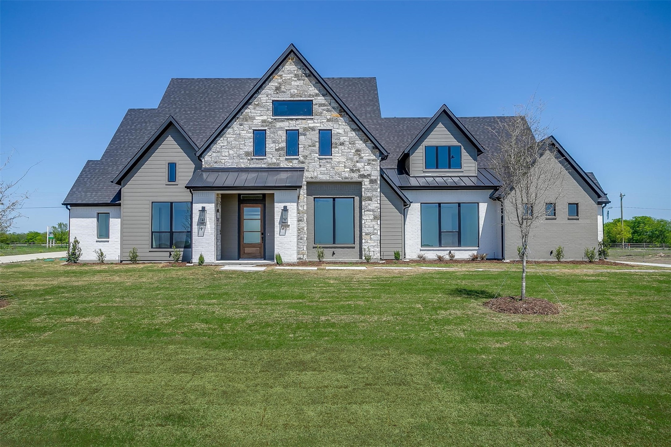 Two-story house with a stone facade, multiple gables, and a broad front lawn.
