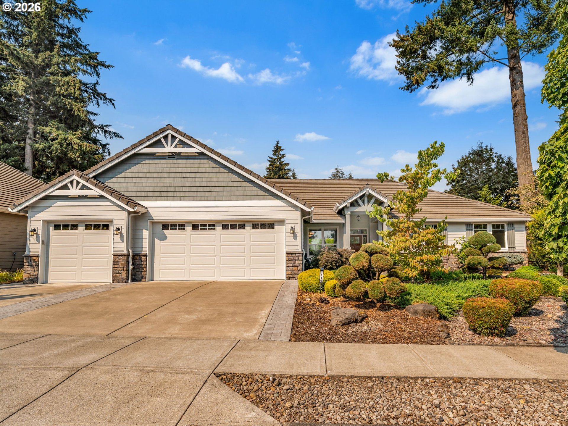 Single-story home with a three-car garage, stone accents, and landscaped front yard.