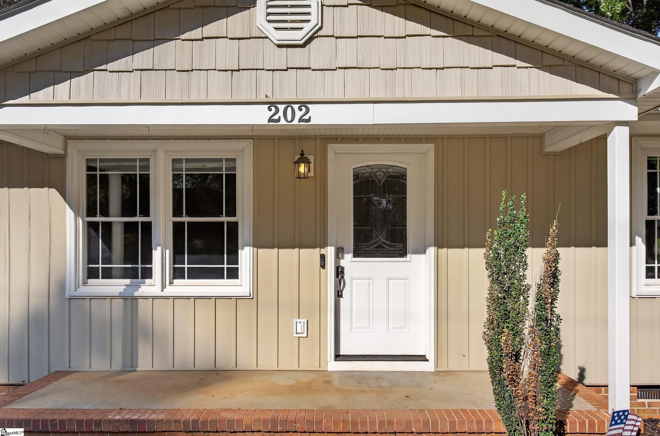 Front entry with a white door, paired windows, and the address 202 above the porch.