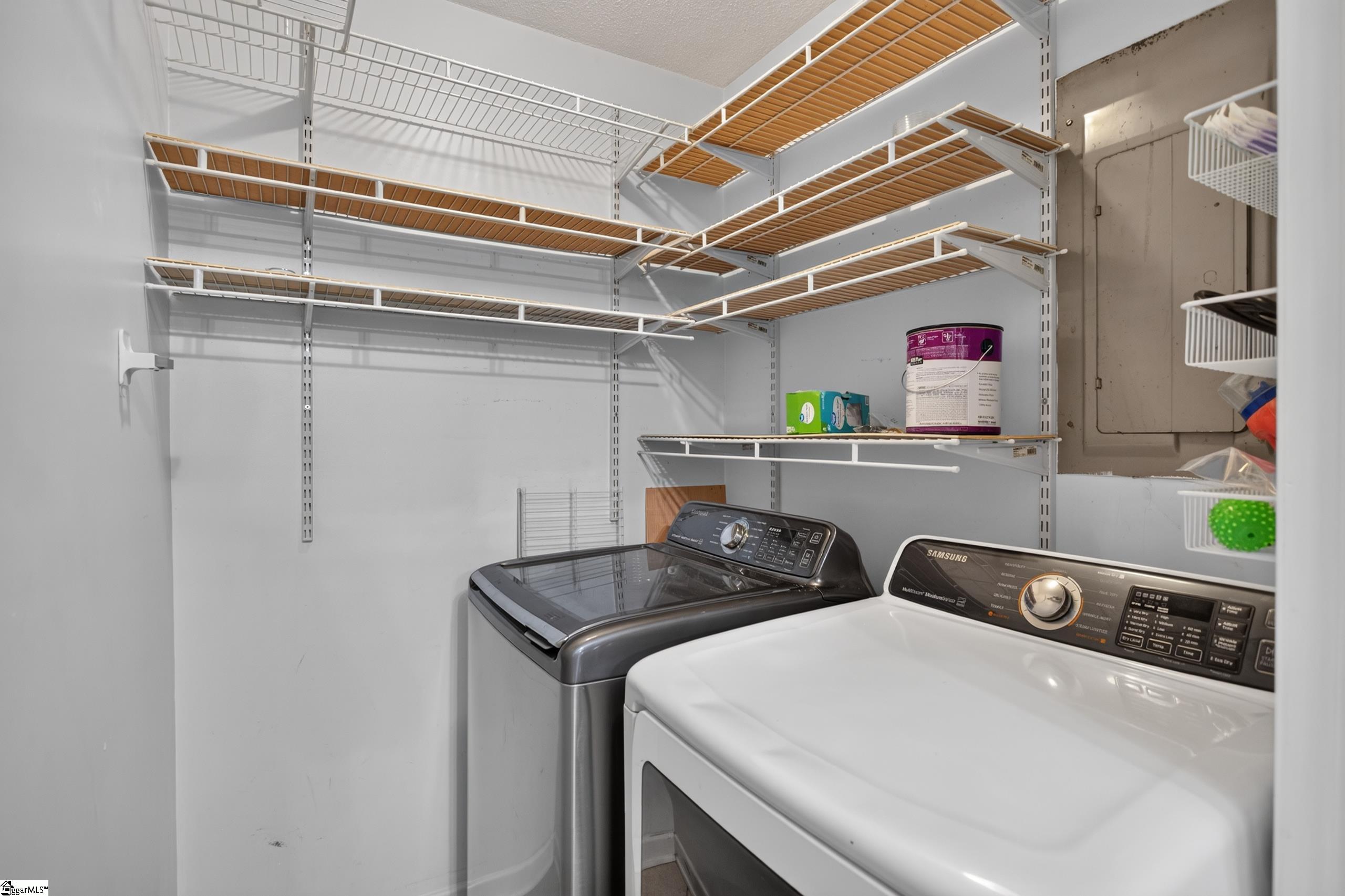 Laundry room with a front-loading dryer, top-loading washer, and extensive wire shelving.