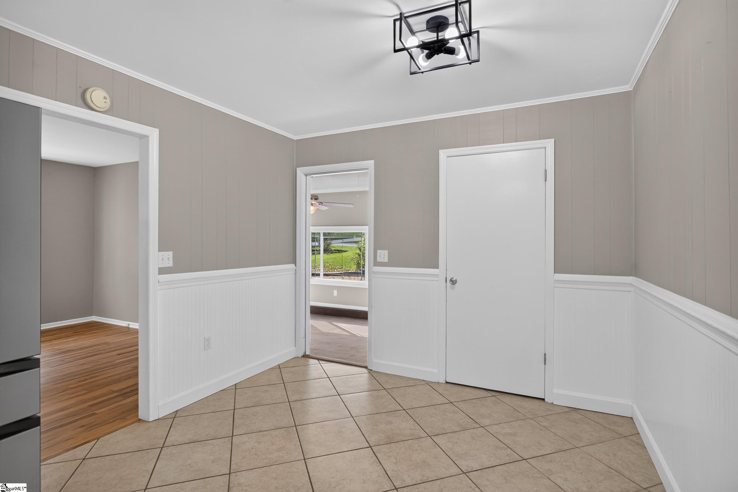 Tiled room with gray paneled walls, white wainscoting, and doorways to adjoining rooms.
