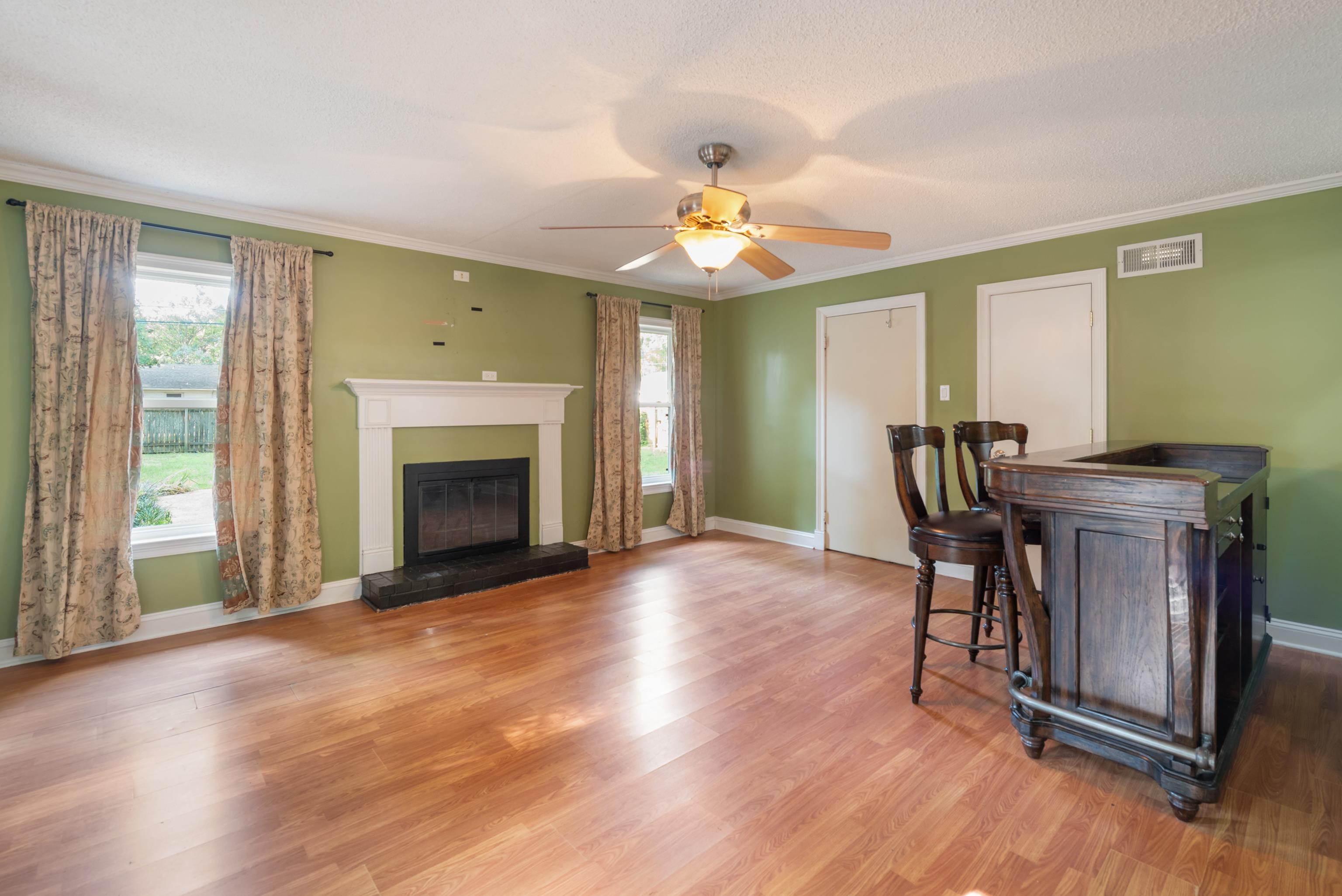 Living room with a white-mantel fireplace, sage-green walls, and a dark wooden bar table.
