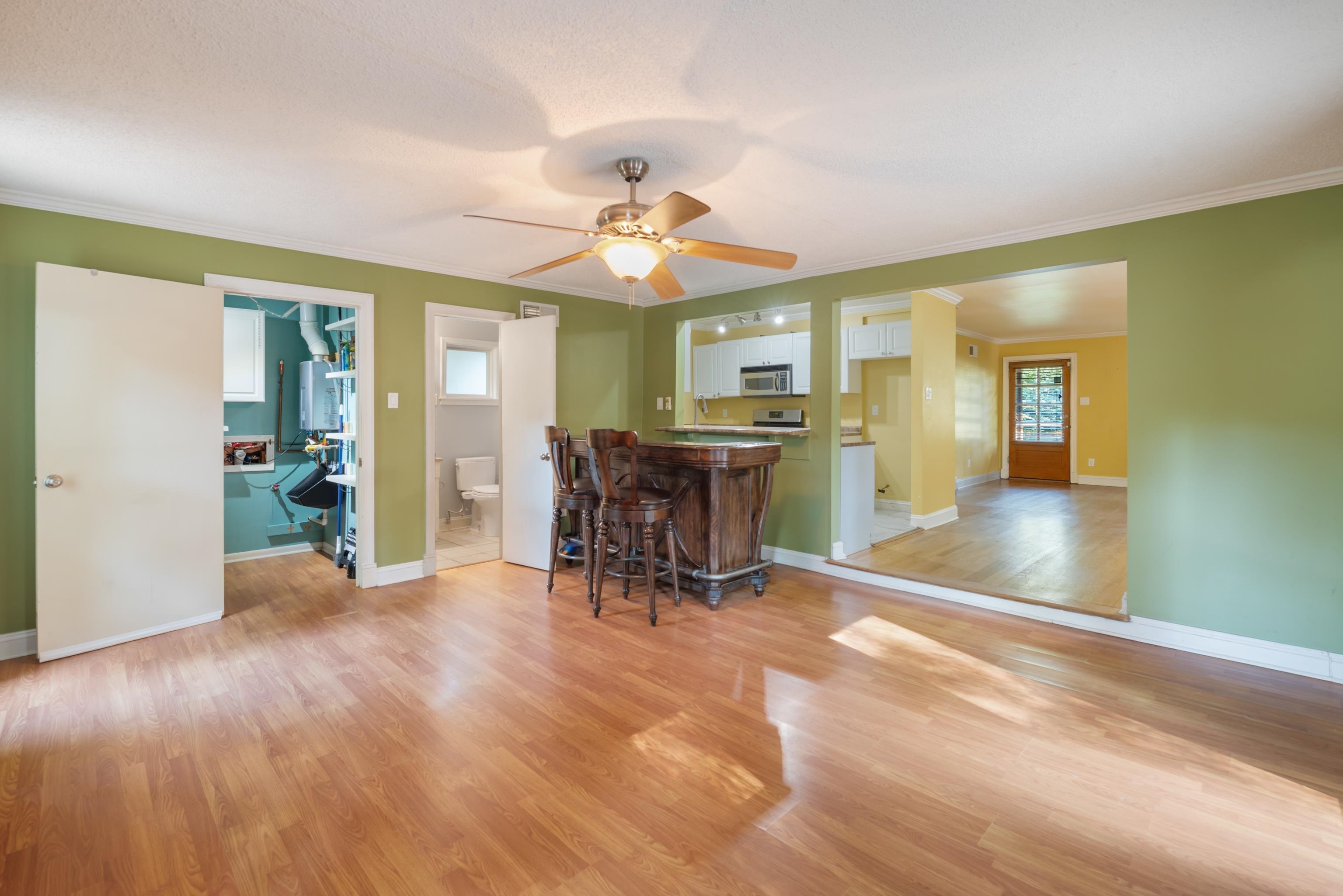 Dining area with green walls, hardwood floors, and a dark wood breakfast bar with stools.