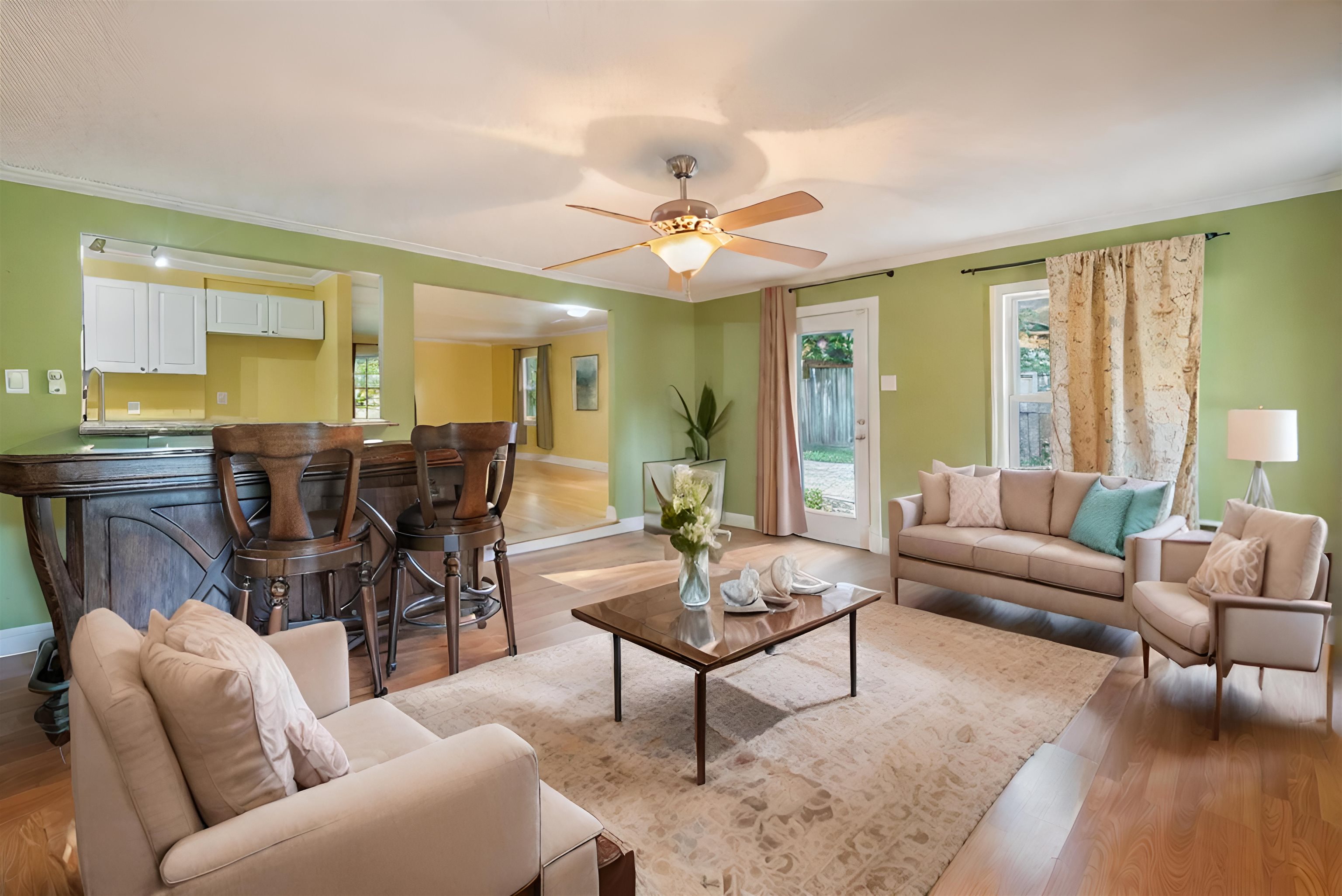 Living room with pale green walls, hardwood floors, and an open kitchen and dining area.