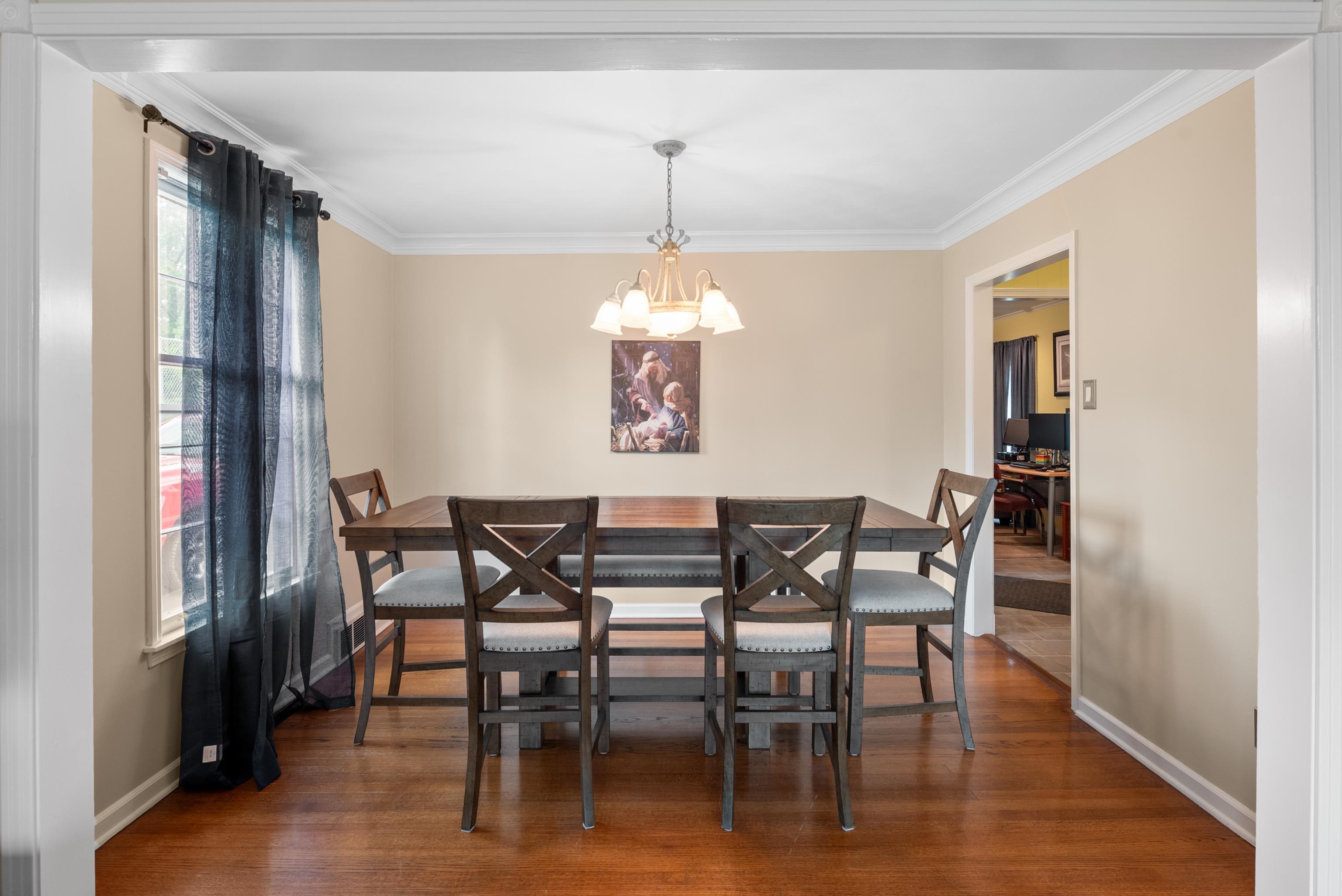 Dining room with a dark wood table, six chairs, chandelier, and hardwood floors.
