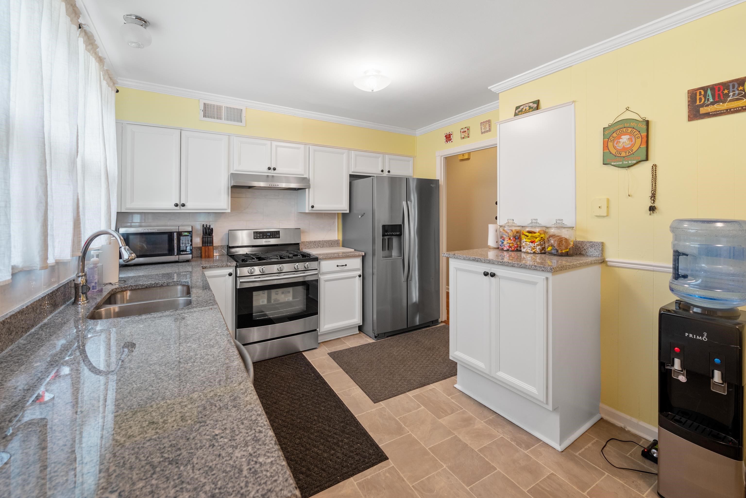 Kitchen with white cabinets, granite counters, stainless steel appliances, and yellow walls.