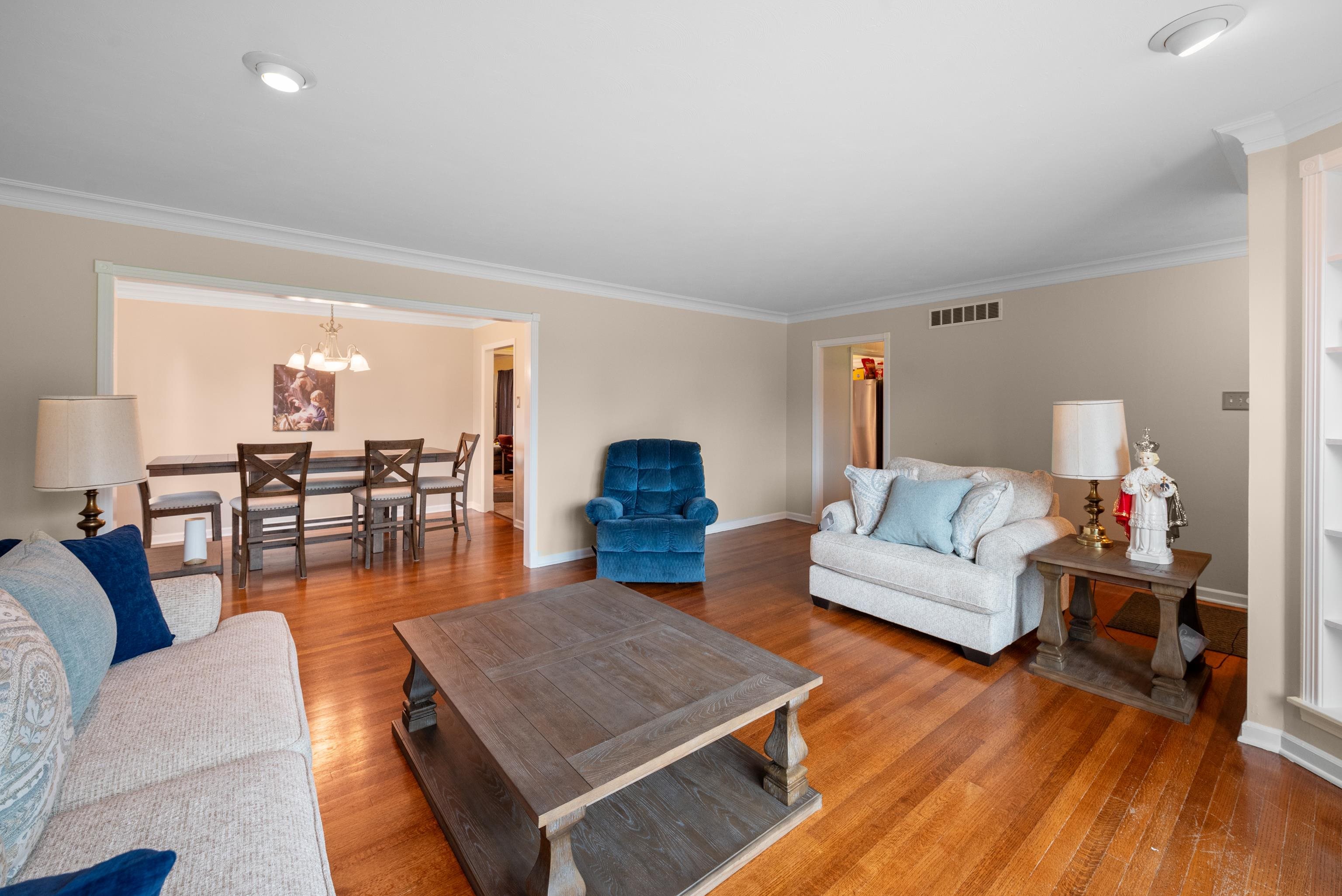 Living room with hardwood floors, blue accent chair, wood coffee table, and adjoining dining area.