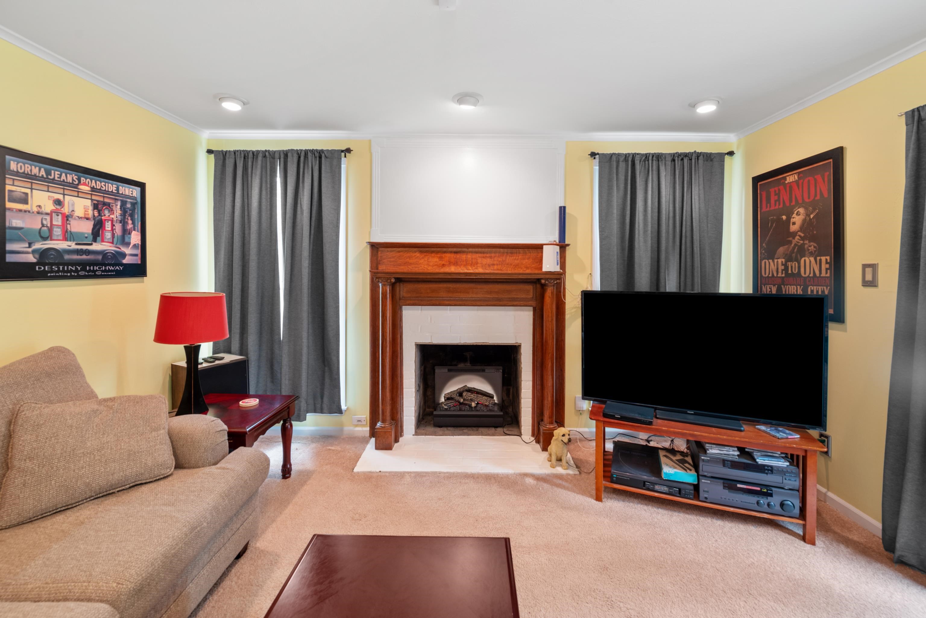 Living room with a wooden fireplace, beige sofa, and large television.