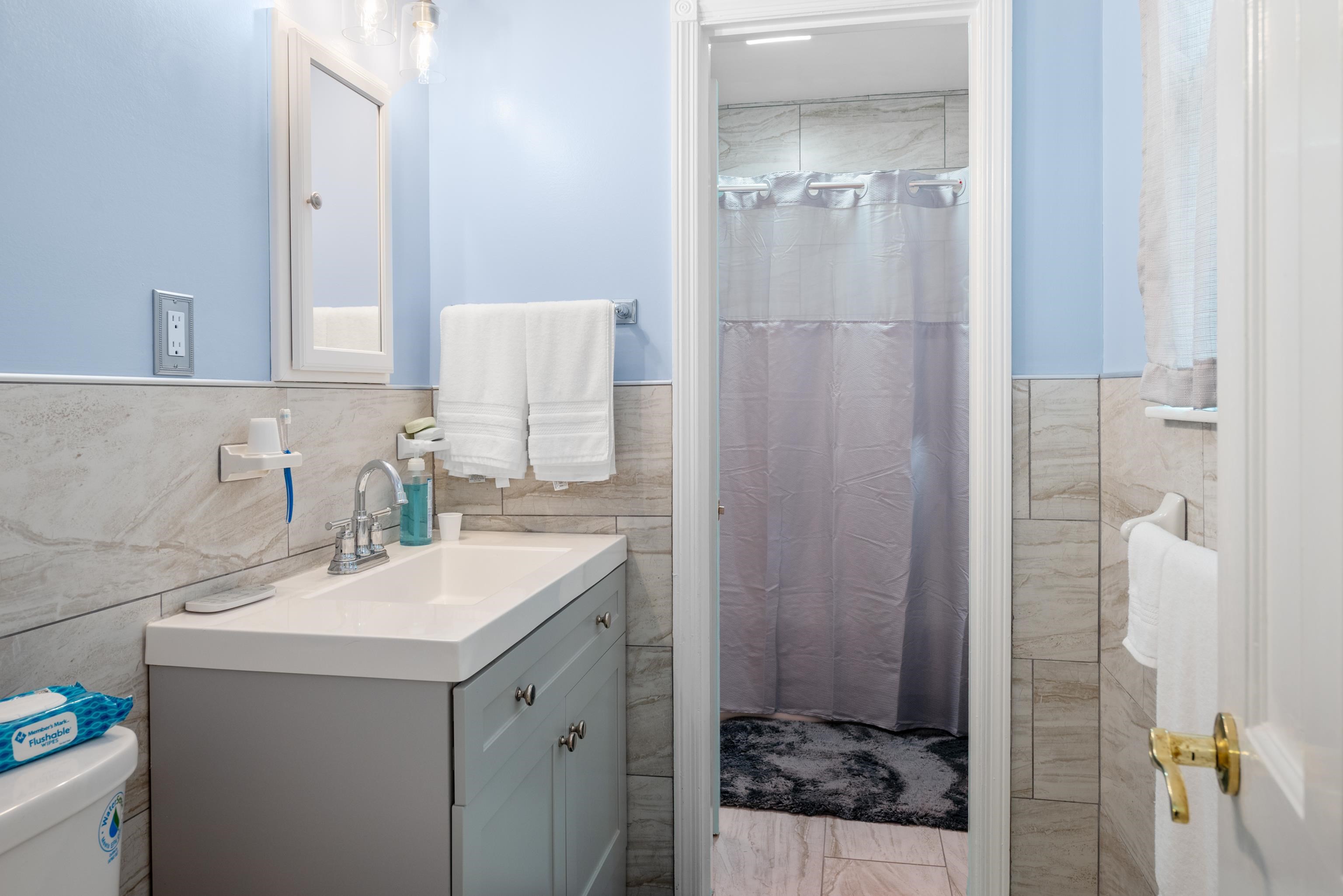 Bathroom with a gray vanity, stone-look tile, and gray shower curtain.