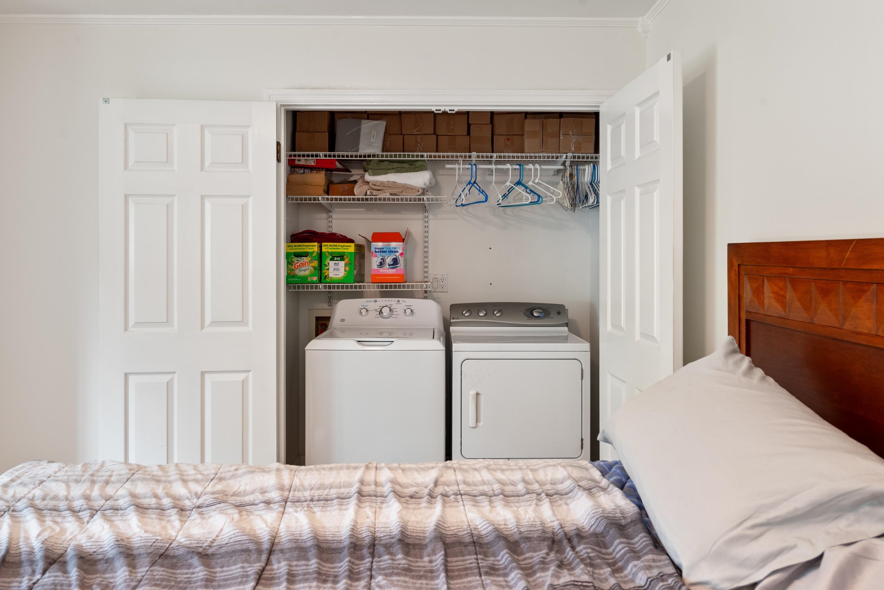 Bedroom with an open laundry closet containing a washer and dryer.