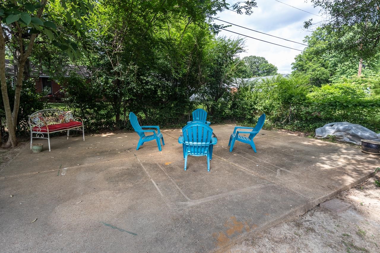 Shaded concrete patio with bright blue Adirondack chairs and a patterned-cushion bench.