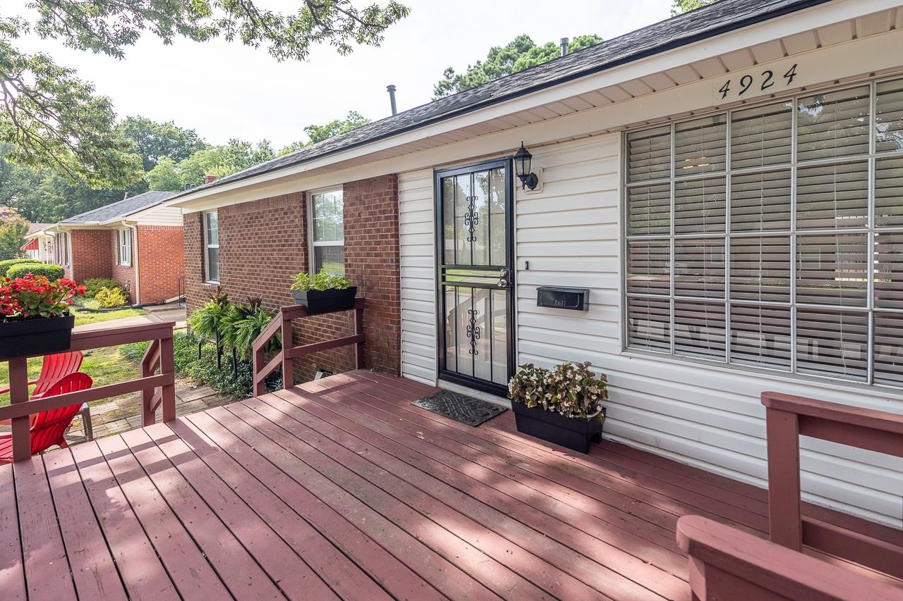 Home exterior with a raised wood deck, brick and white siding, and a decorative metal security door.