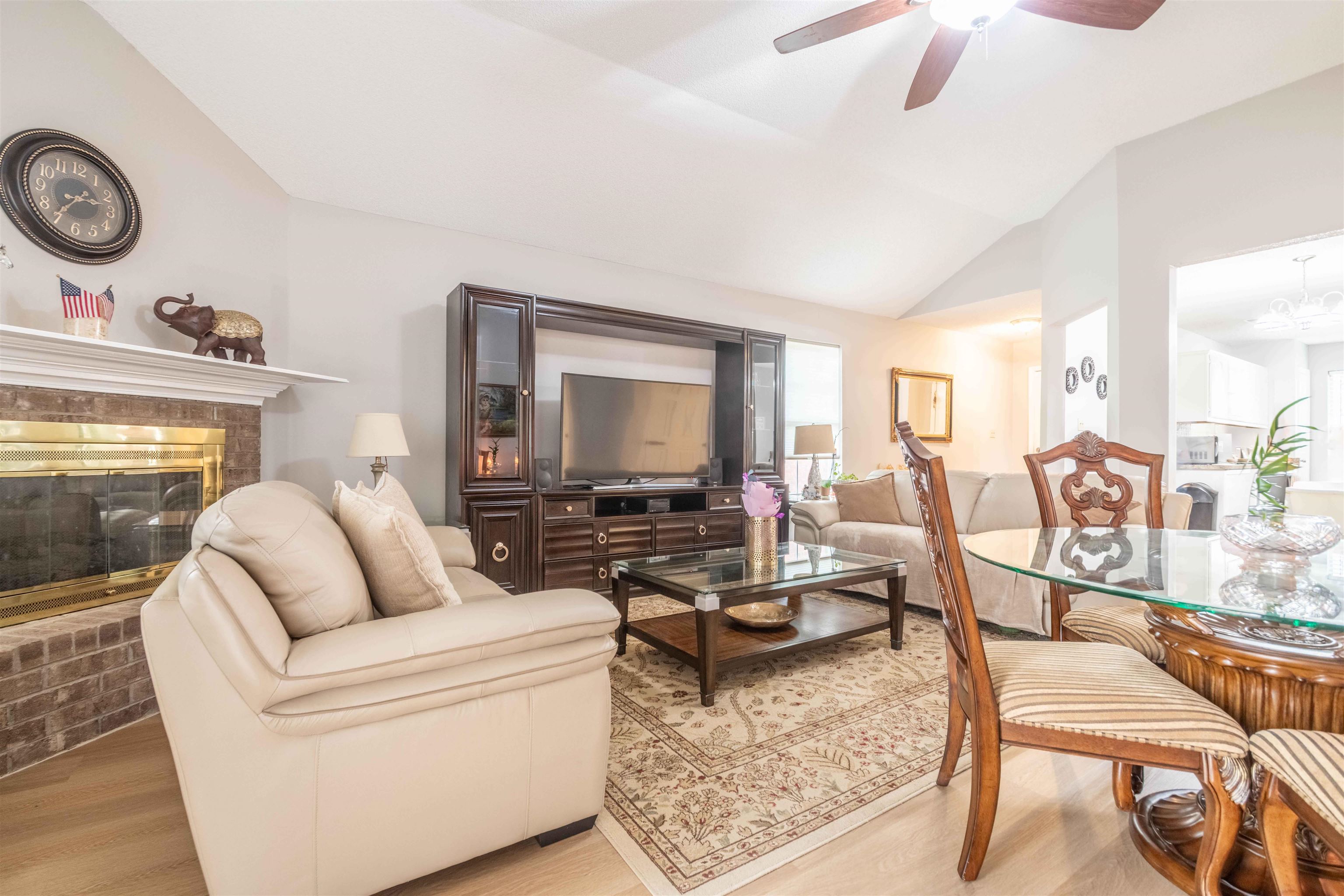 Living room with brick fireplace, cream leather seating, and adjoining dining area.
