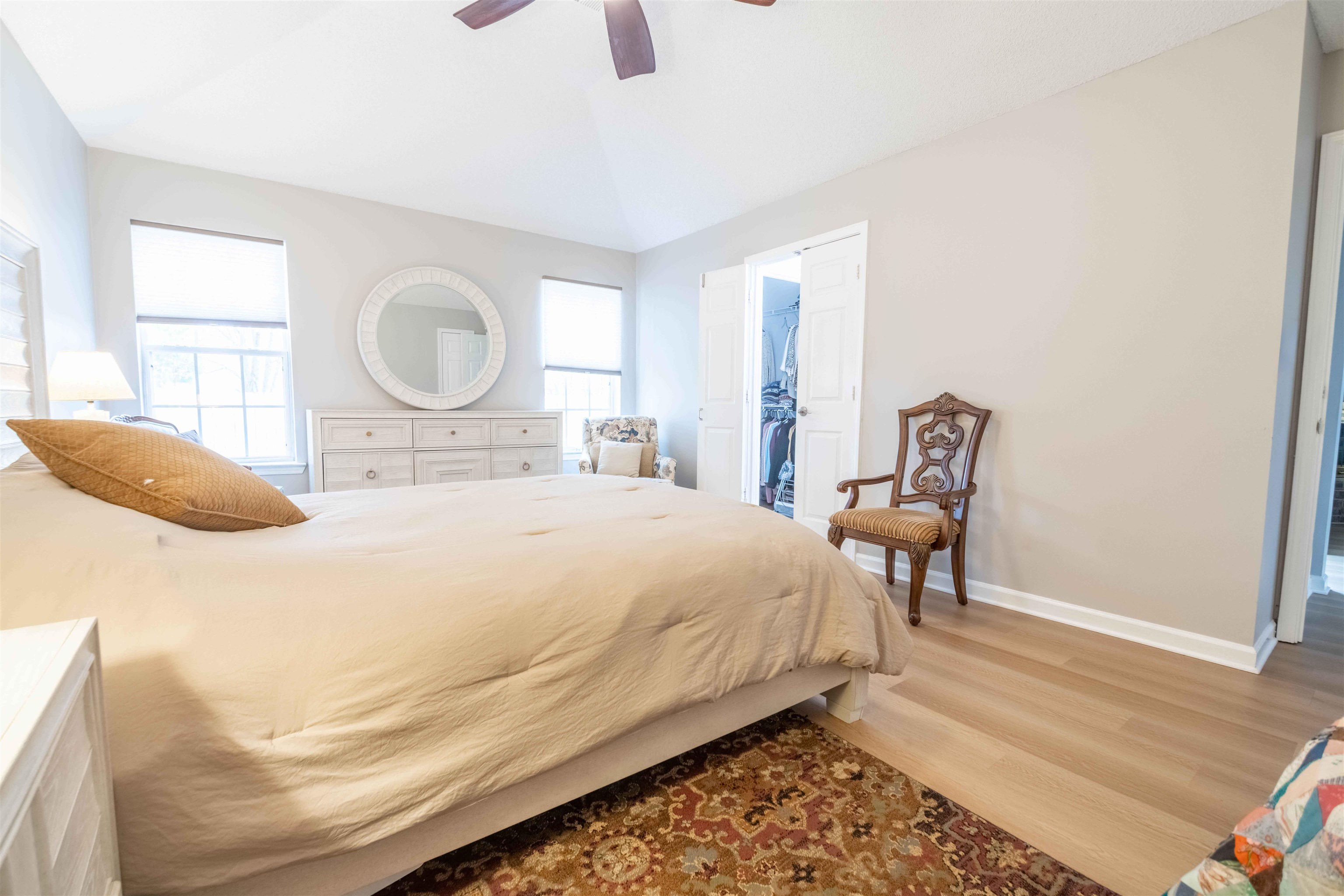 Furnished bedroom with a vaulted ceiling, light wood floors, and an open closet.