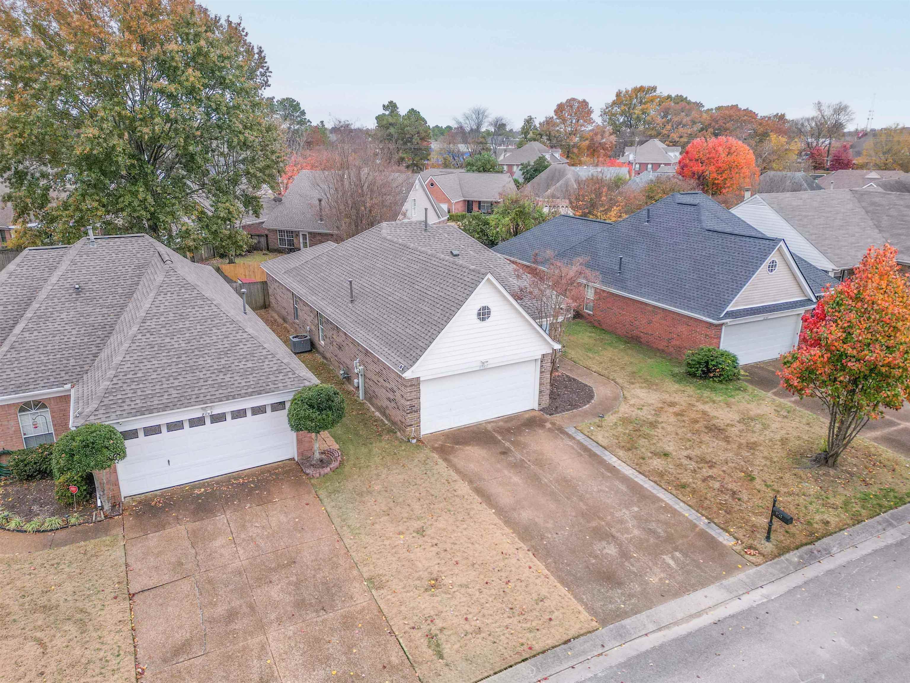 Aerial view of a single-story brick home with an attached garage and driveway.