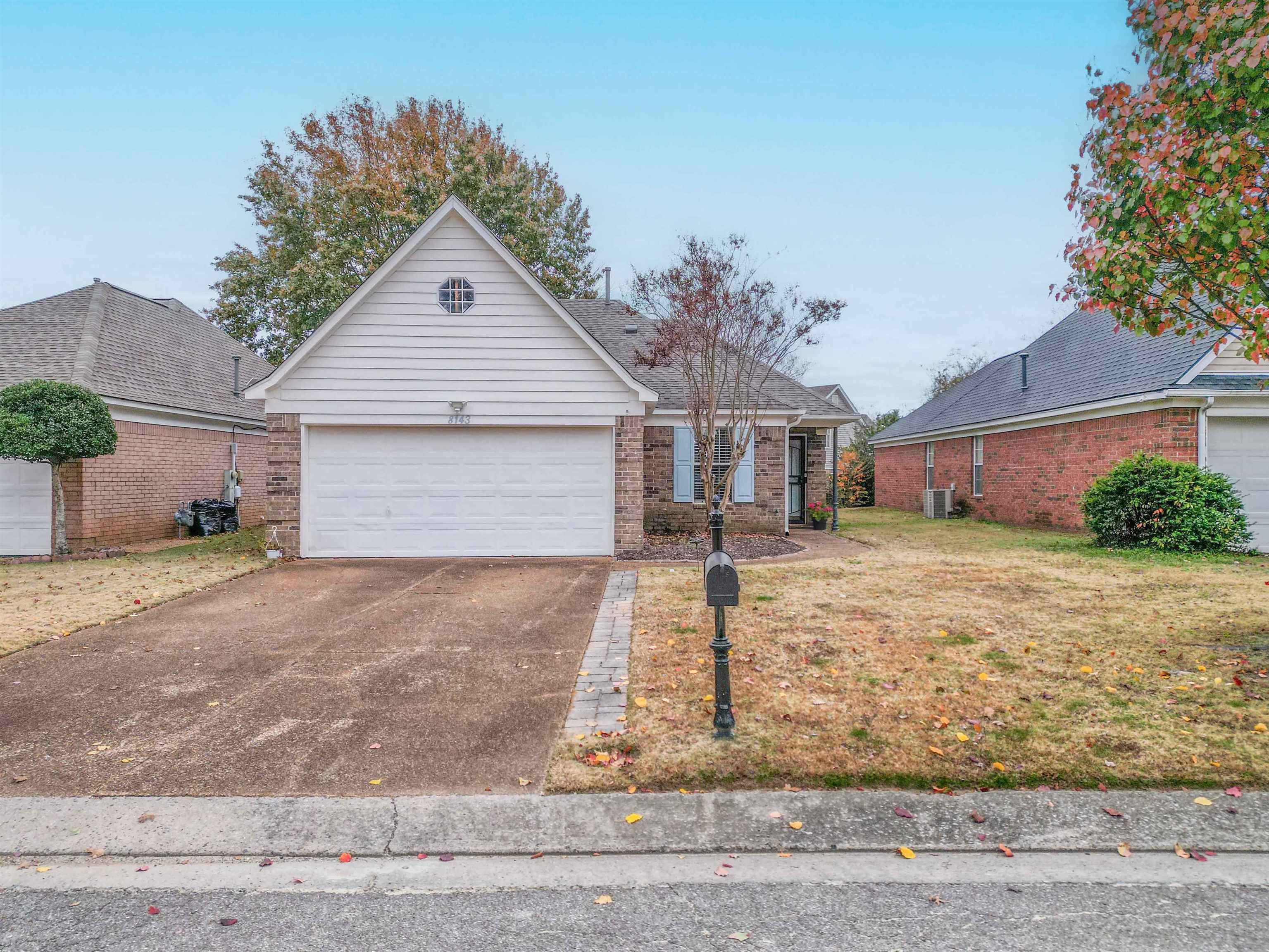 Brick house with a white gable, double garage, and mailbox beside the driveway.