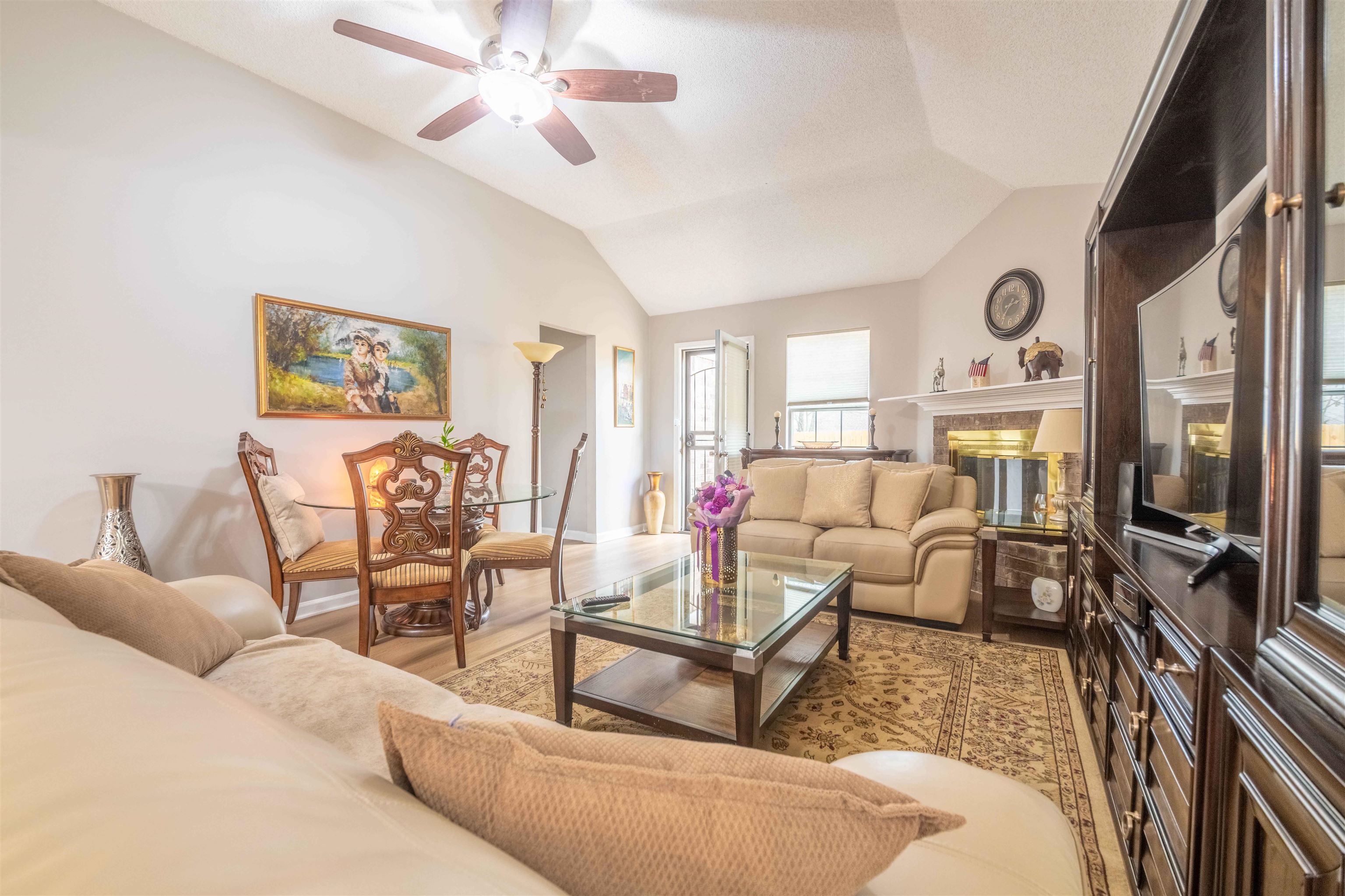 Furnished living room with vaulted ceiling, brick fireplace, and built-in entertainment center.