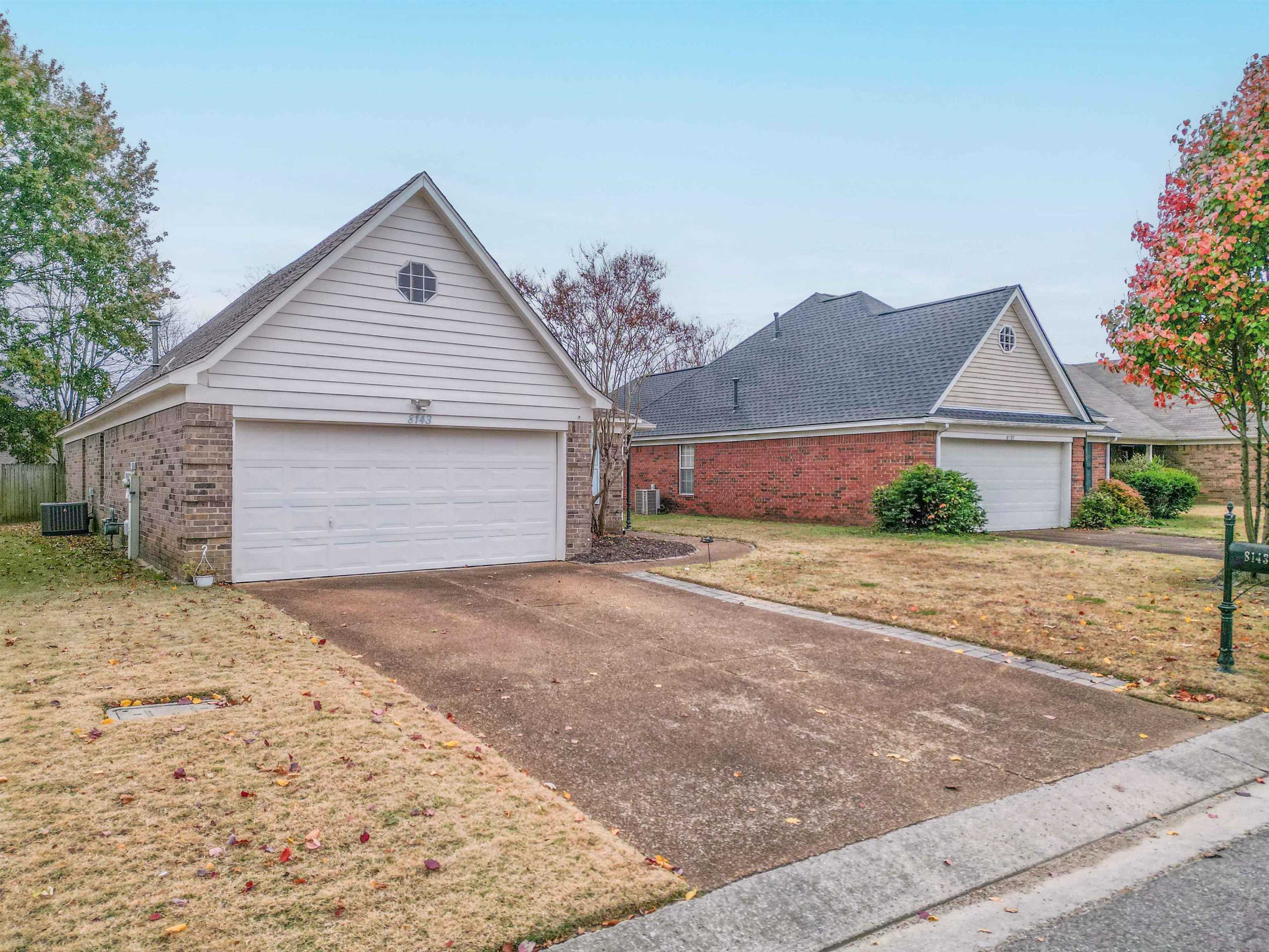 Home exterior with a prominent white double garage door, gabled roof, and wide driveway.