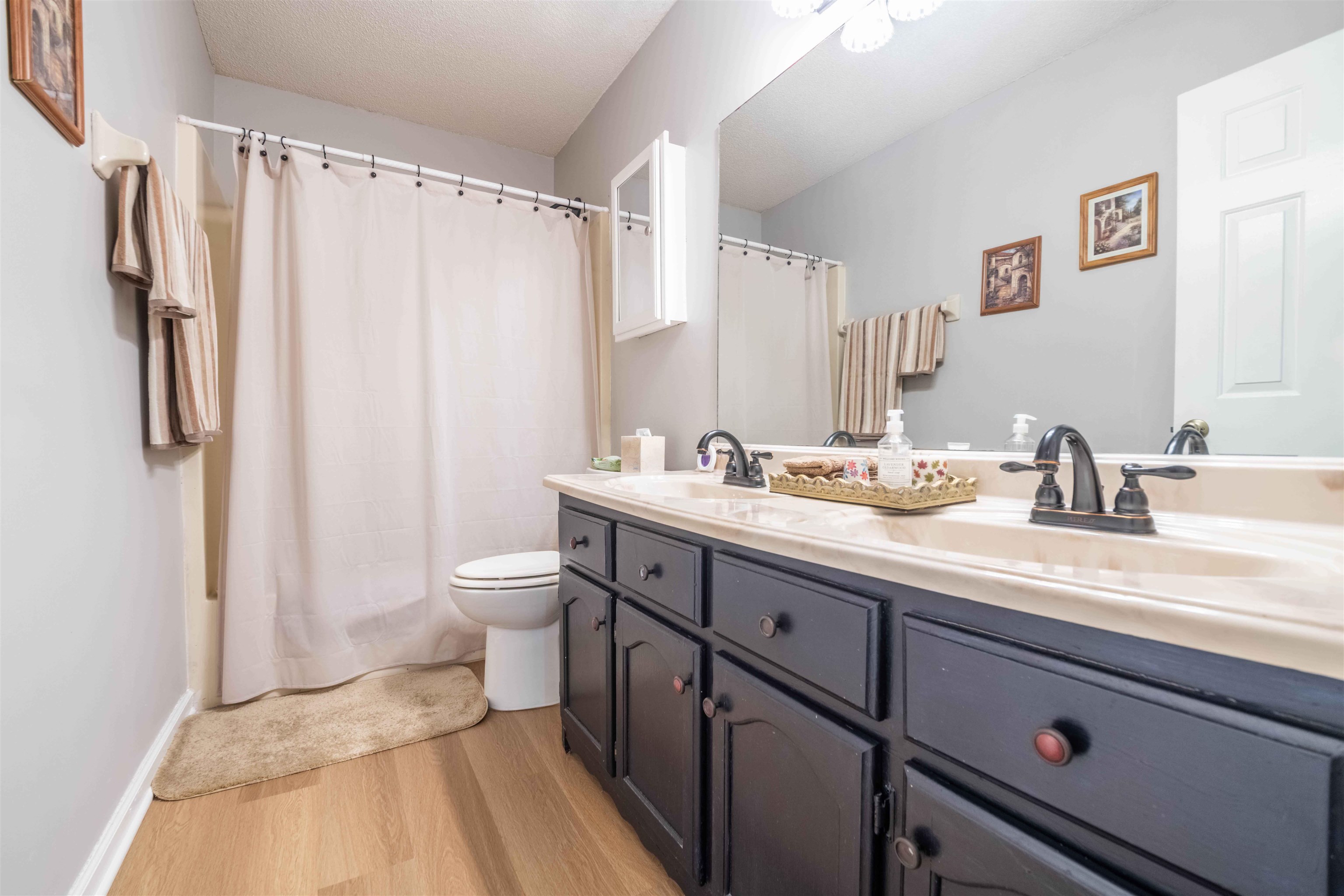 Bathroom with a long dark gray vanity, large mirror, and white shower curtain.
