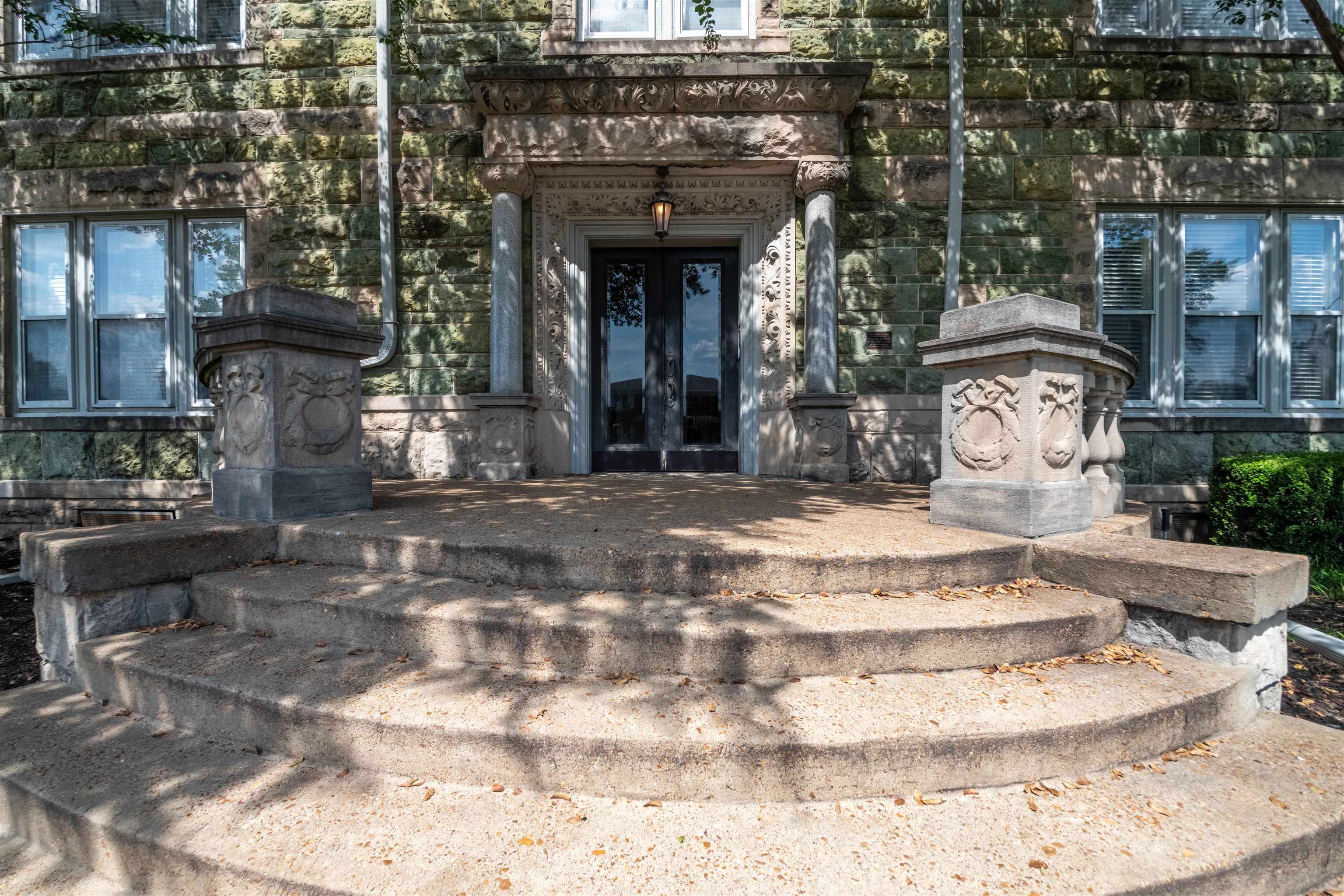 Stone building entrance with an ornate carved doorway and broad curved steps.