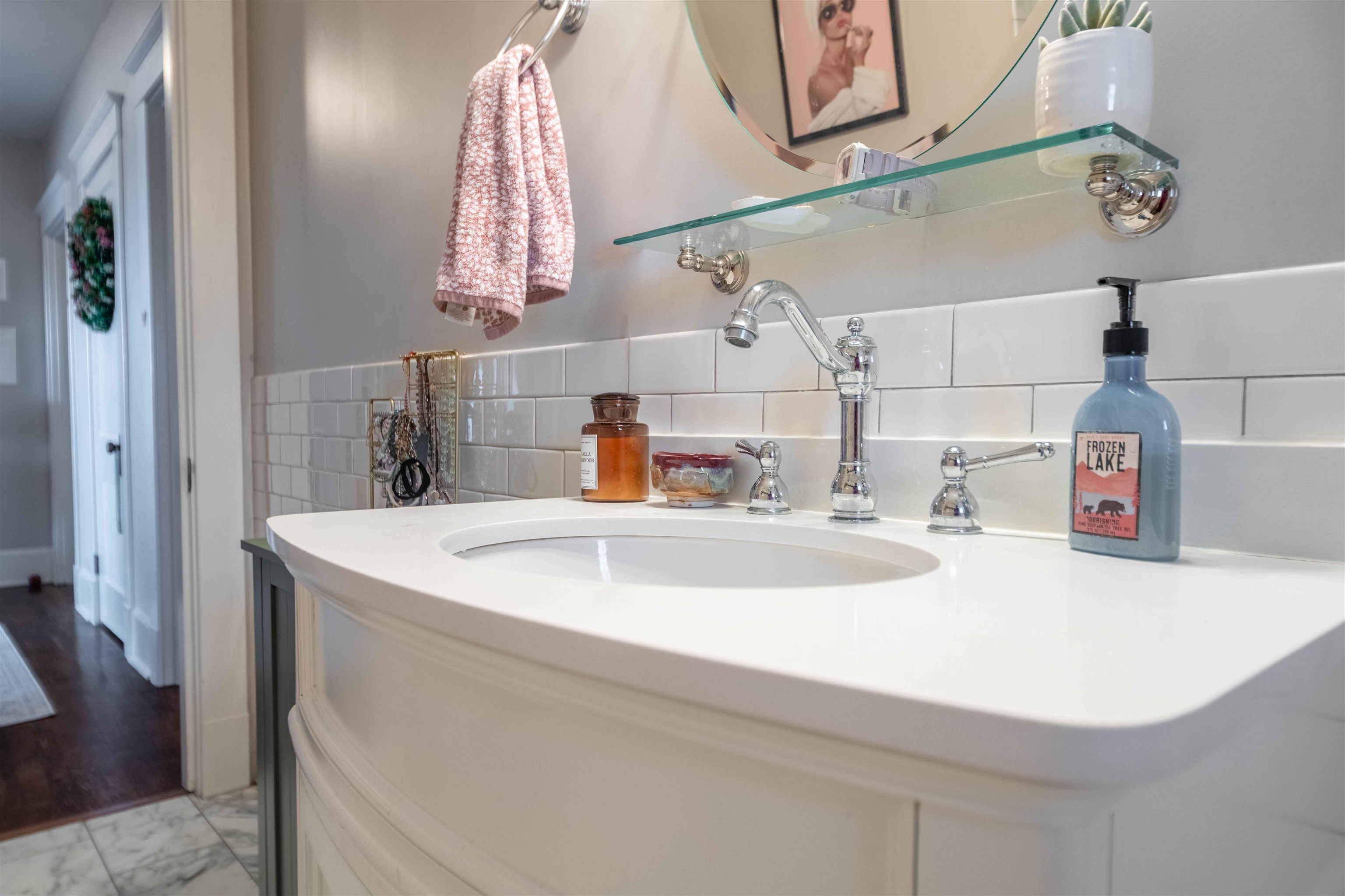 Bathroom vanity with a wide white sink, chrome fixtures, subway tile, and a pink hand towel.