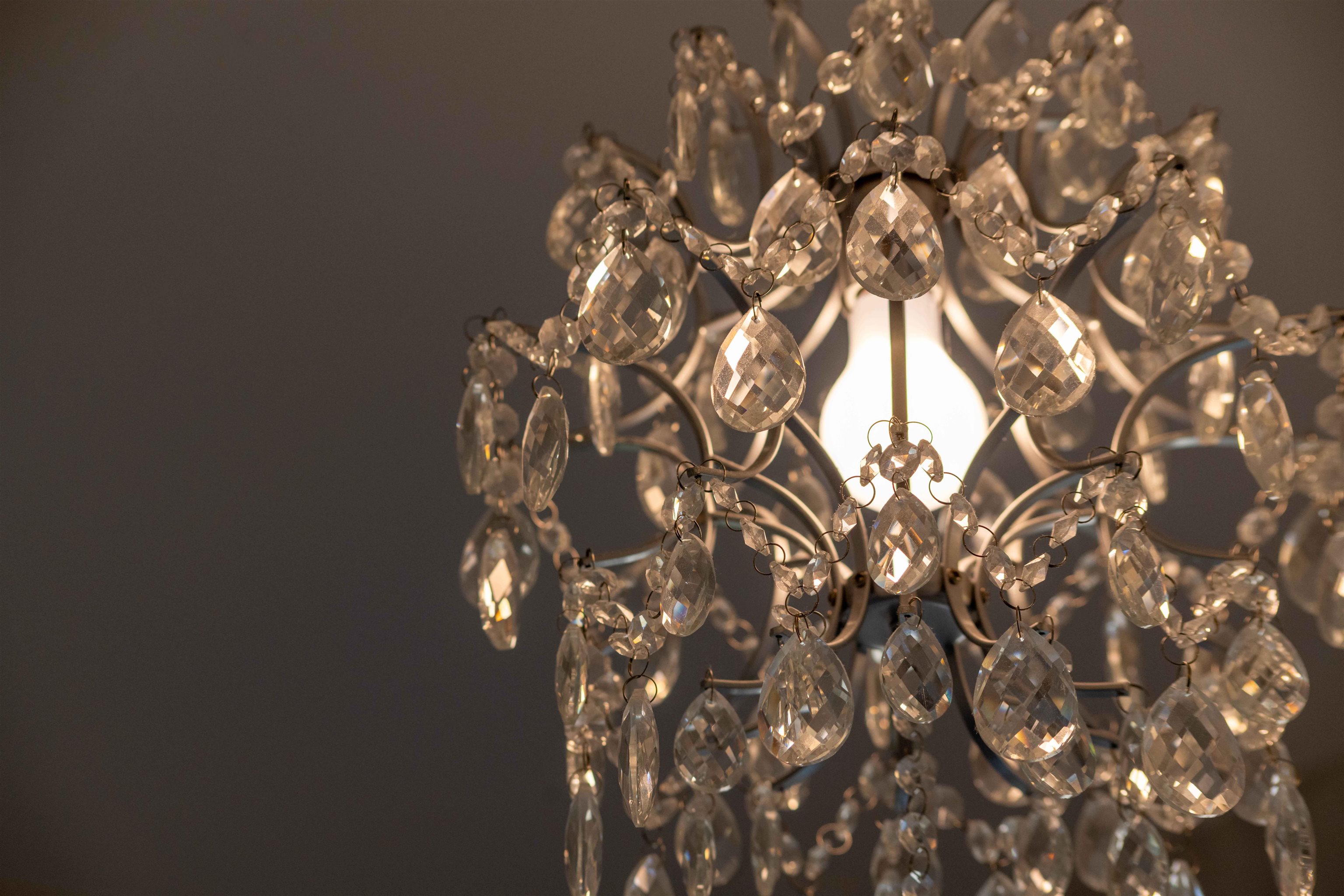Crystal chandelier with faceted hanging drops glowing warmly.