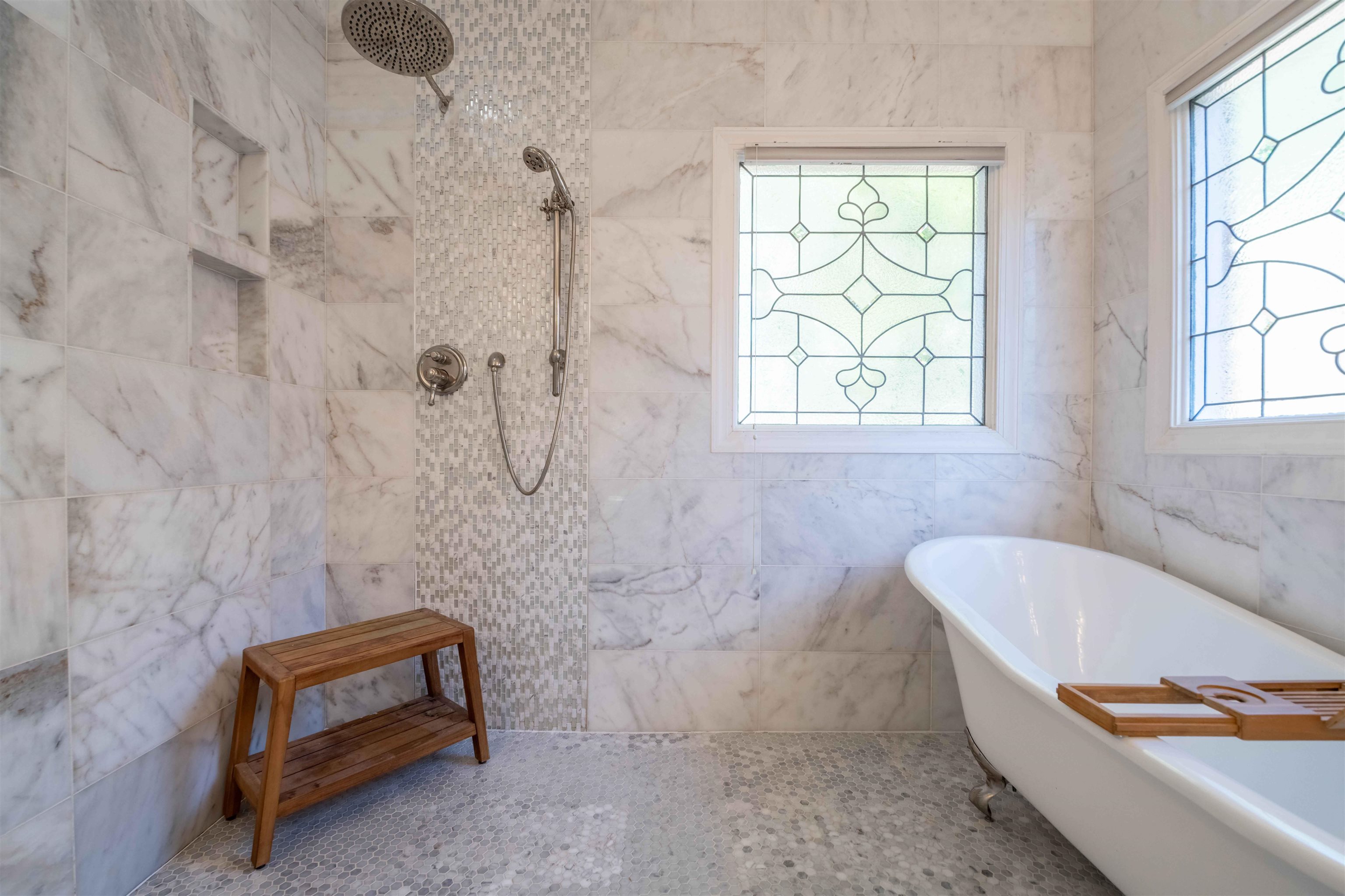 Marble-tiled bathroom with a freestanding tub, glass-paneled windows, and a walk-in shower.