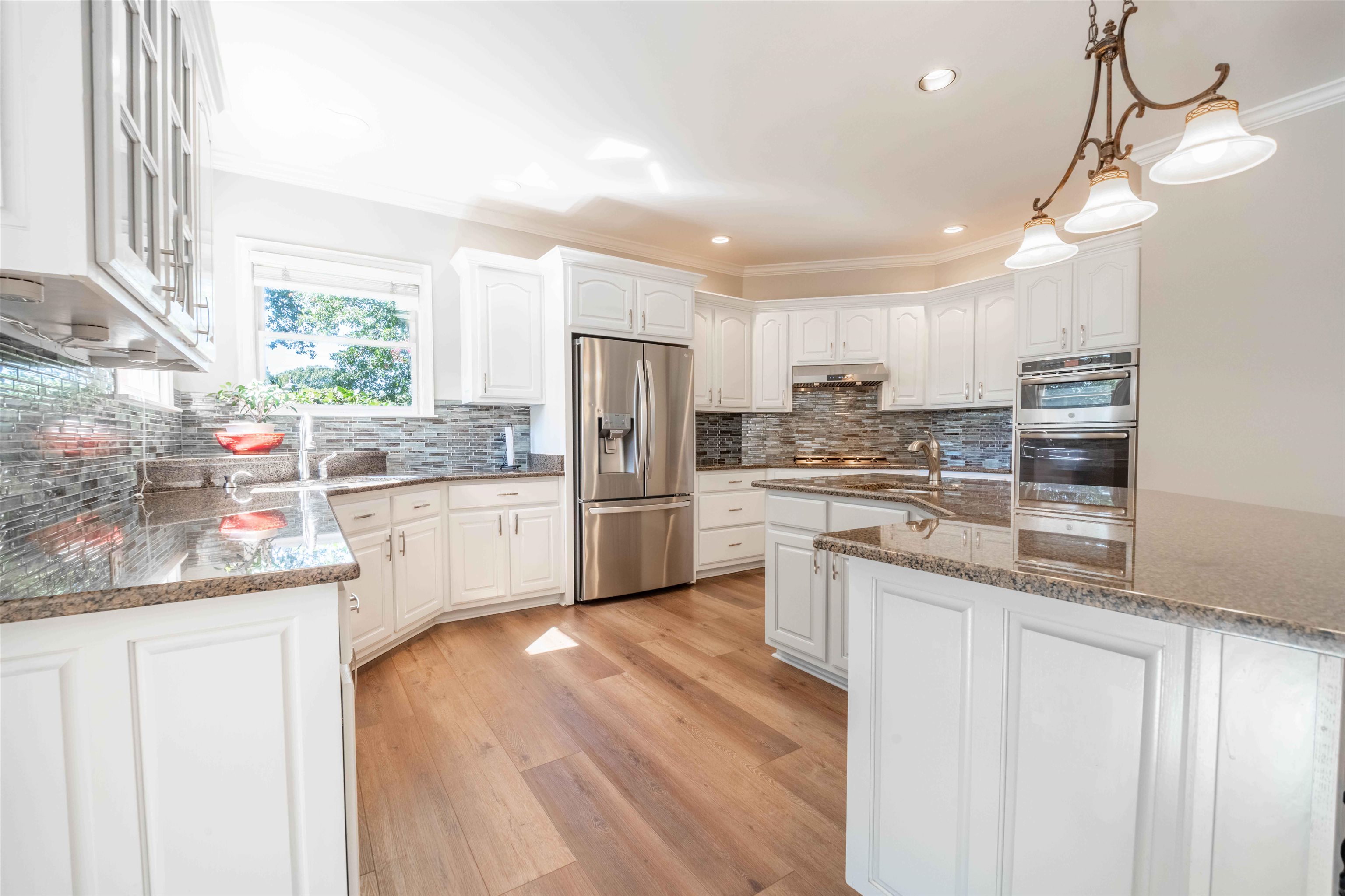 Bright kitchen with white cabinetry, stainless steel appliances, granite counters, and a large island.