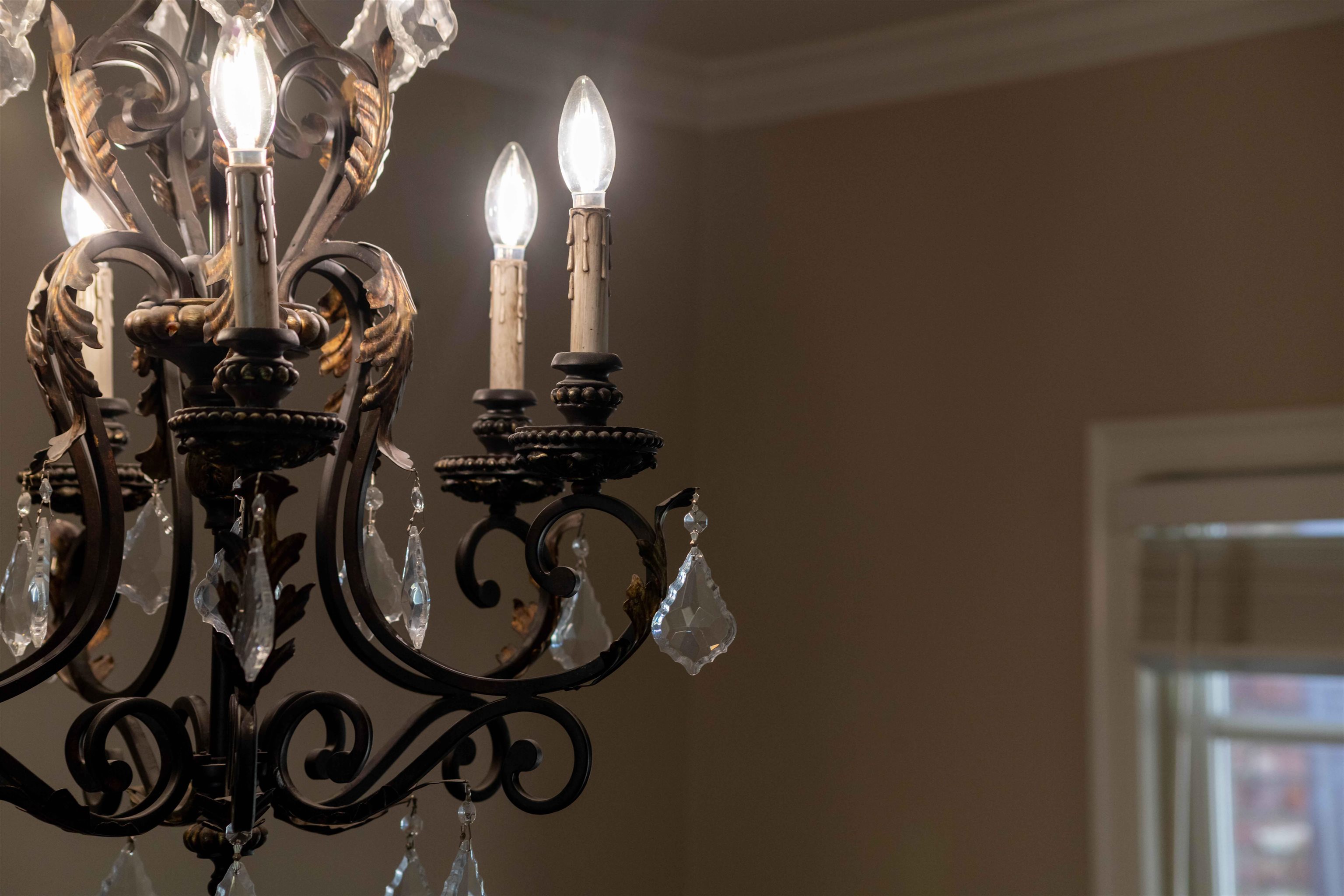 Ornate black iron chandelier with crystal drops and candle-shaped lights.