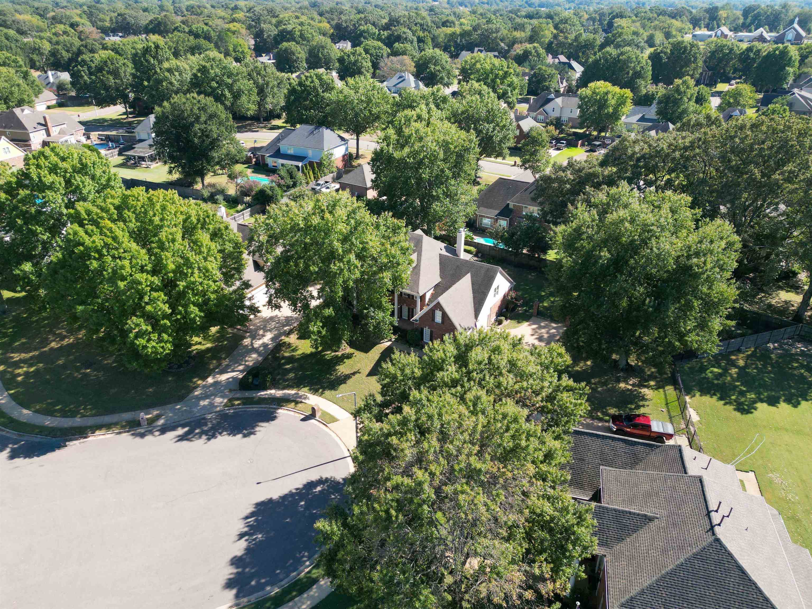 Aerial view of a brick home on a tree-lined cul-de-sac.