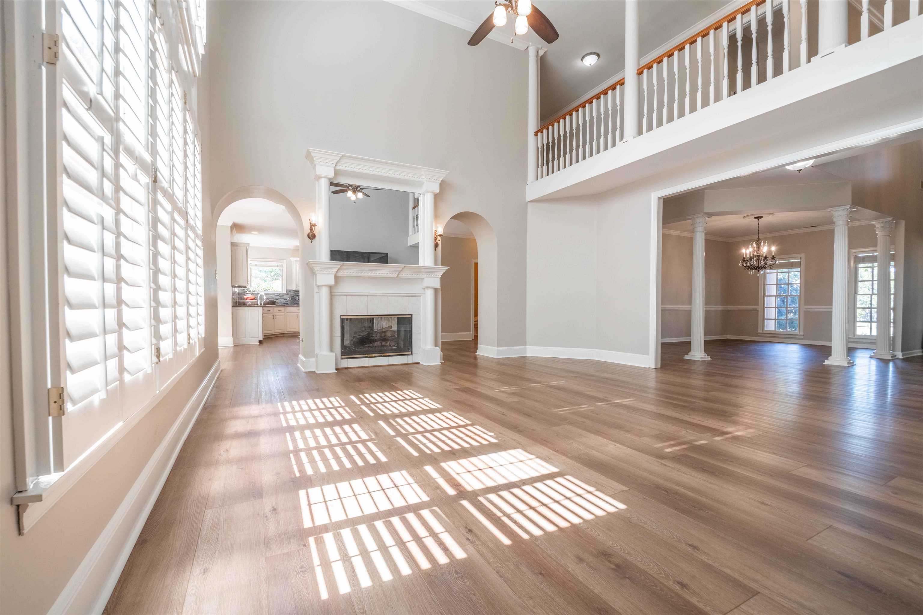 Two-story living room with a fireplace, hardwood floors, and an upstairs gallery overlooking the space.