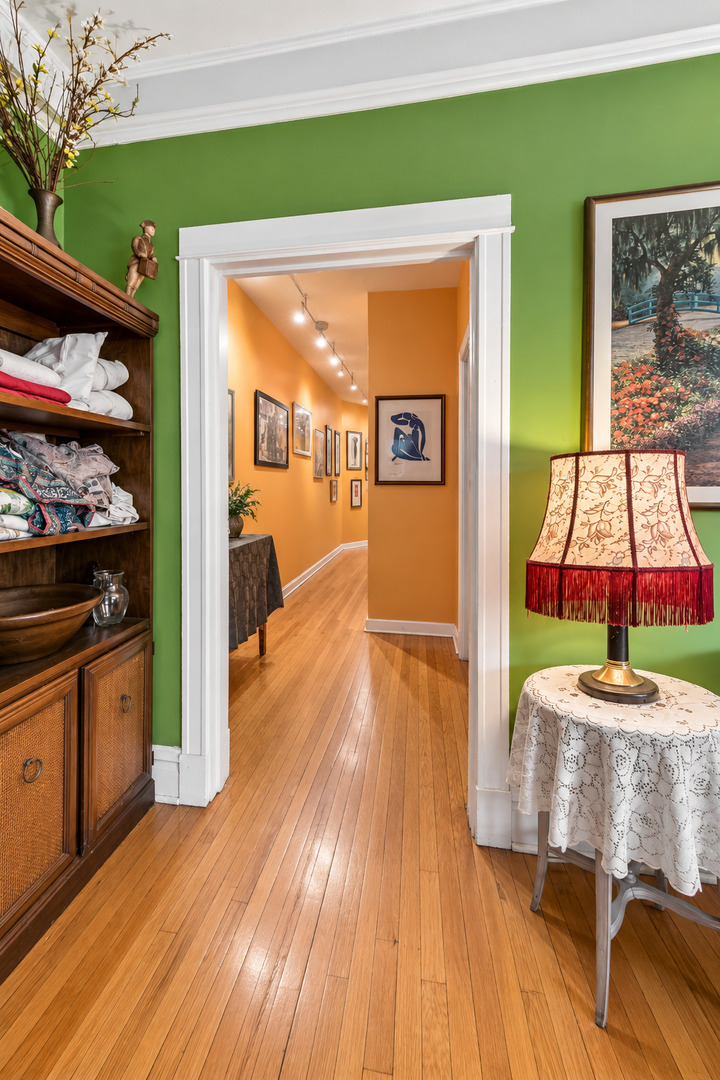 Furnished apartment interior with green walls, hardwood floors, and an orange art-lined hallway.
