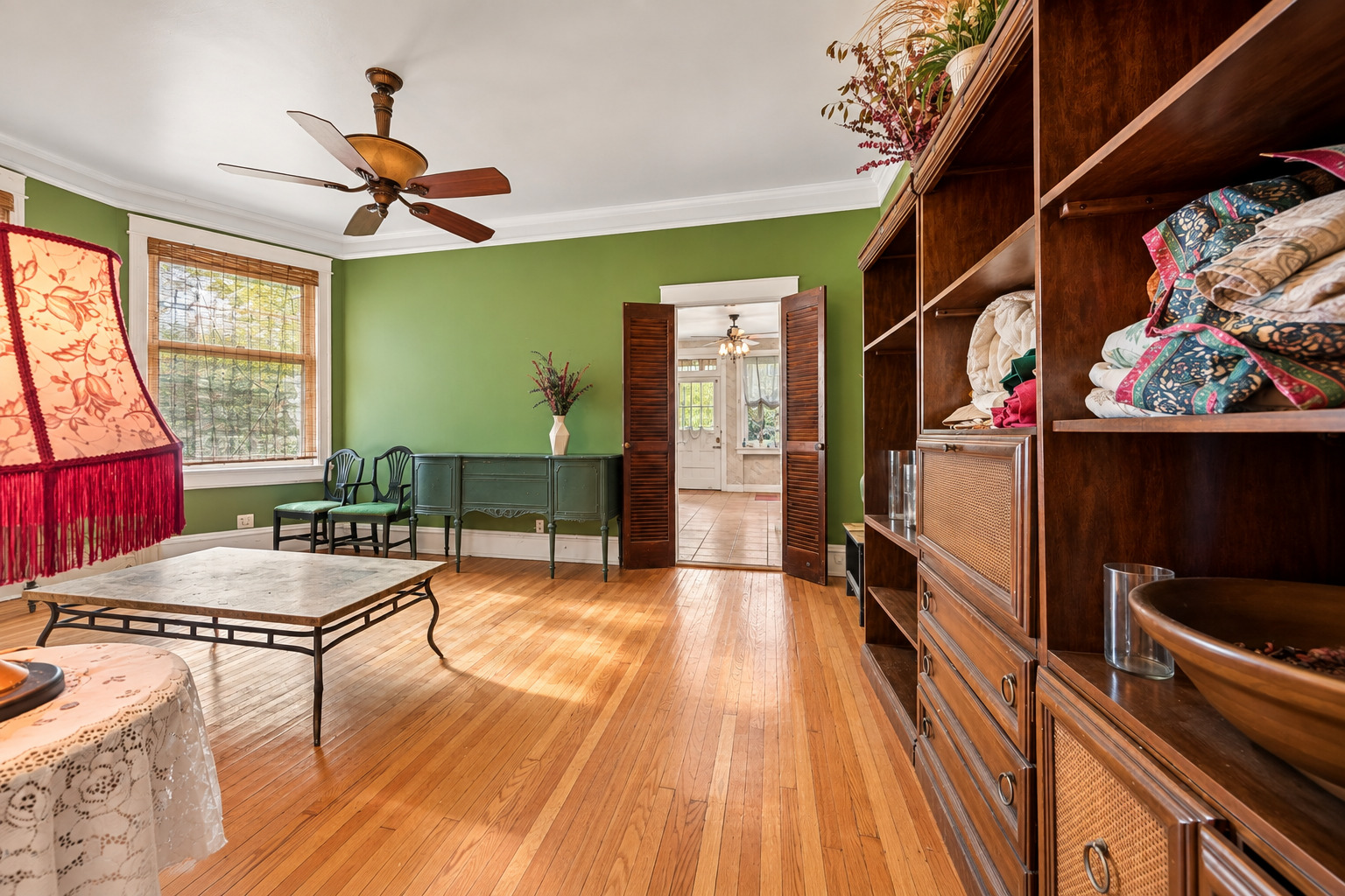 Living room with green walls, hardwood floors, and built-in wooden shelving with cane-front cabinets.