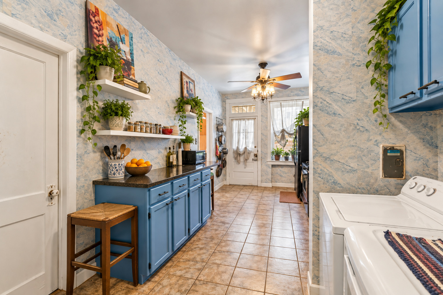 Kitchen with blue cabinets, patterned tile, open shelving, and a washer and dryer.