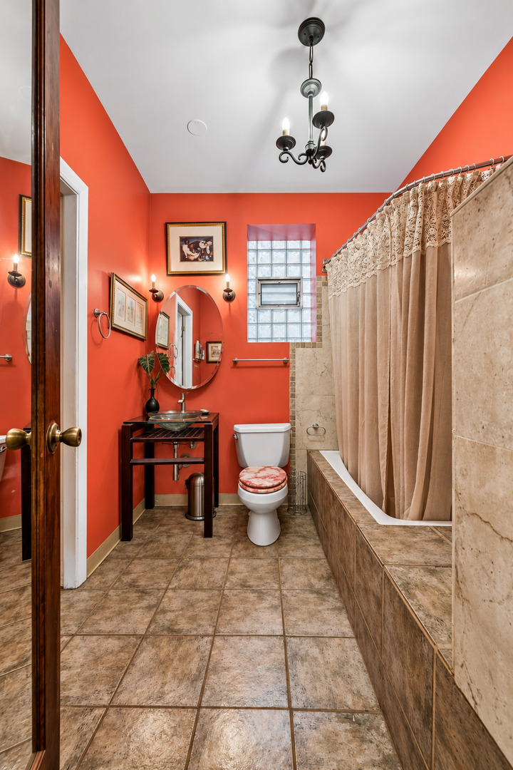 Bathroom with coral walls, a glass-block window, and a bathtub with a lace-trimmed shower curtain.