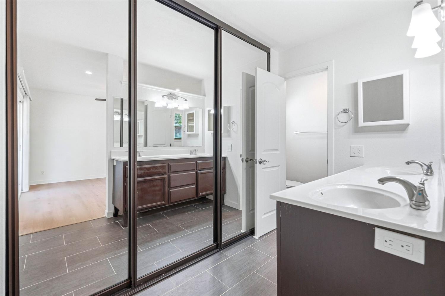 Bathroom with a double-sink vanity, large mirrors, and gray tile flooring.