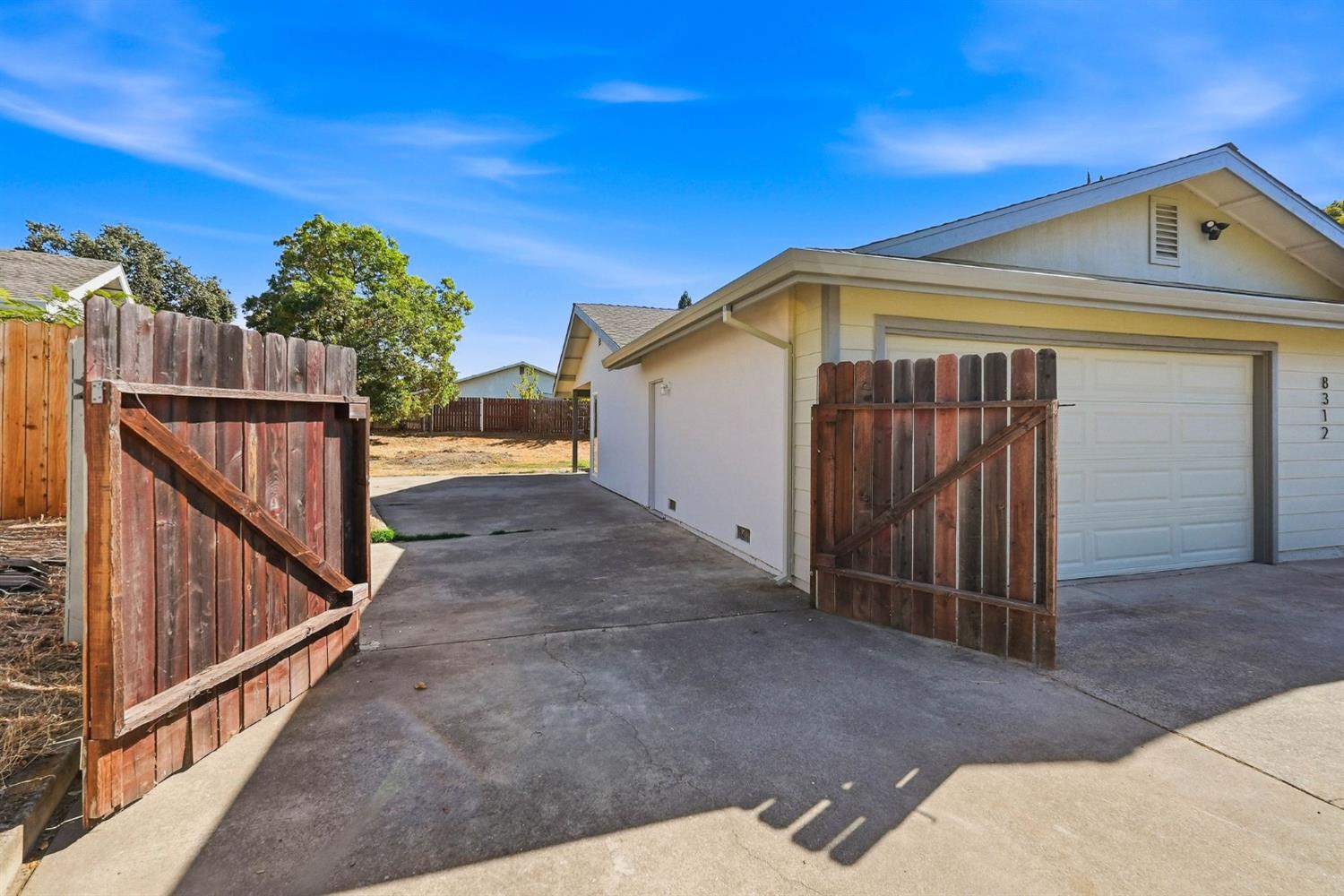 House garage and driveway behind open wooden gates.