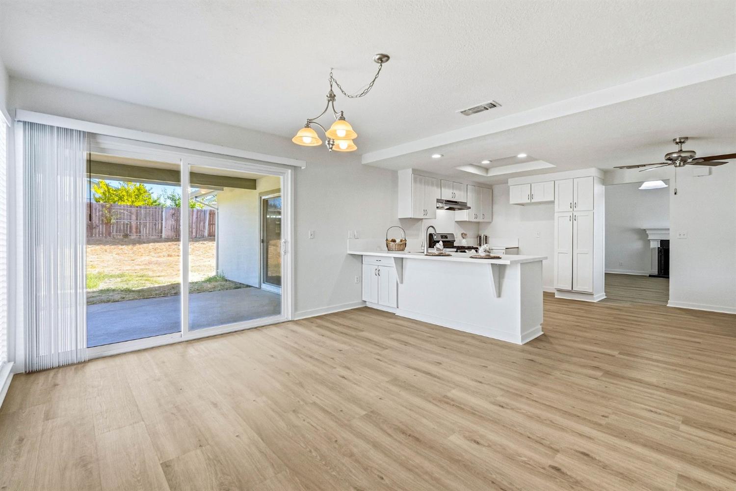 Open-plan kitchen with white cabinets, a peninsula, and sliding doors to the backyard.