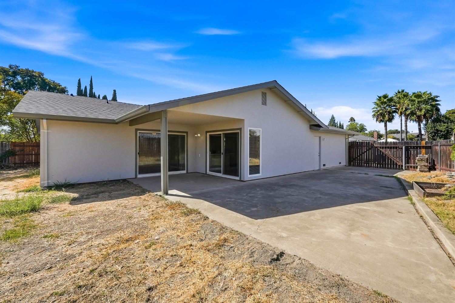 Single-story home with a covered patio and wide paved backyard area.