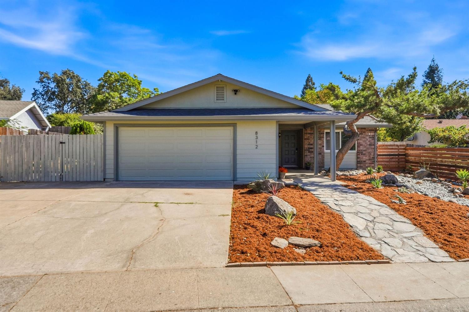 Single-story home with a wide garage, stone walkway, and drought-tolerant front landscaping.