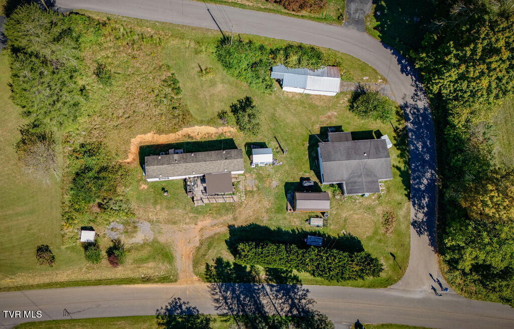 Aerial view of a rural property with several buildings, lawn, and roads along two sides.