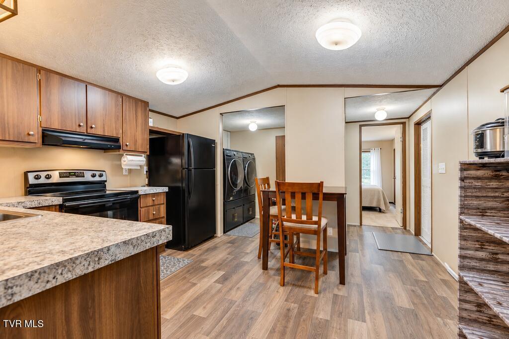 Kitchen with wood cabinets and black appliances, dining table, and laundry nook with washer and dryer.