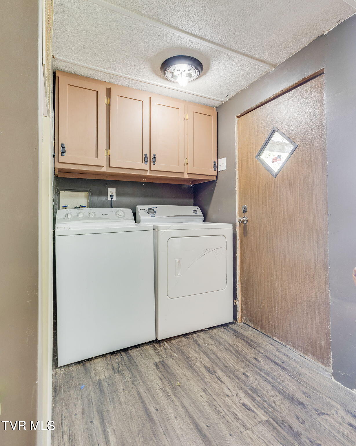 Laundry room with a washer and dryer beneath tan cabinets.