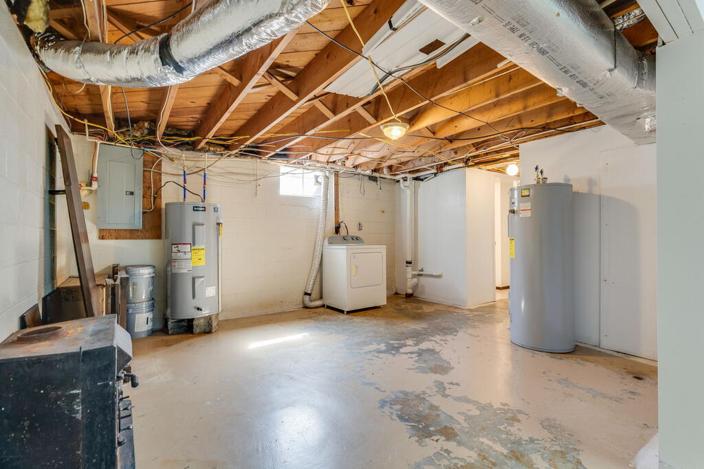 Basement utility room with exposed joists, two water heaters, and a washer and dryer.
