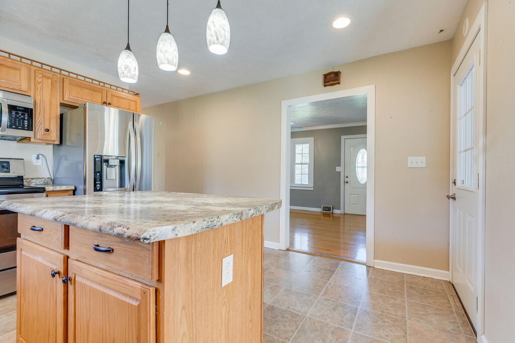 Kitchen with a large stone-topped island, honey-colored cabinets, and stainless steel appliances.